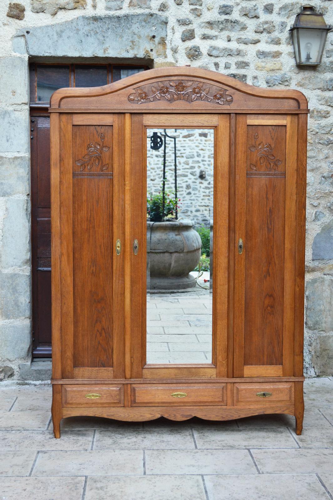 Beautiful bedroom wardrobe in solid oak carved with flowers.

This cabinet consists of a beautifully carved pediment, 3 doors, one of which has a beveled mirror, and 3 drawers.
The doors open onto a large wardrobe section on the left and a
