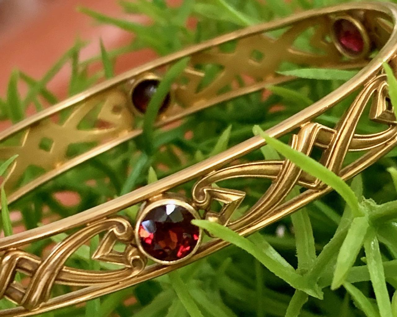 This Art Nouveau 14 karat yellow Gold bangle is made by Whiteside and Blank.  It features beautiful filigree all the way around the bangle, which has been accented with six faceted Garnet stones.  It is stamped 