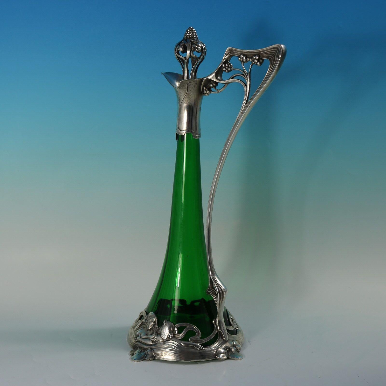 Art Nouveau WMF green glass silver plated claret jug of stylised form, the mount depicting bathing maidens. The handle and finial modelled as a fruiting vine. Impressed maker's marks including 'WMF', 'EP', 'as' and 'I/0' to underside of jug, and