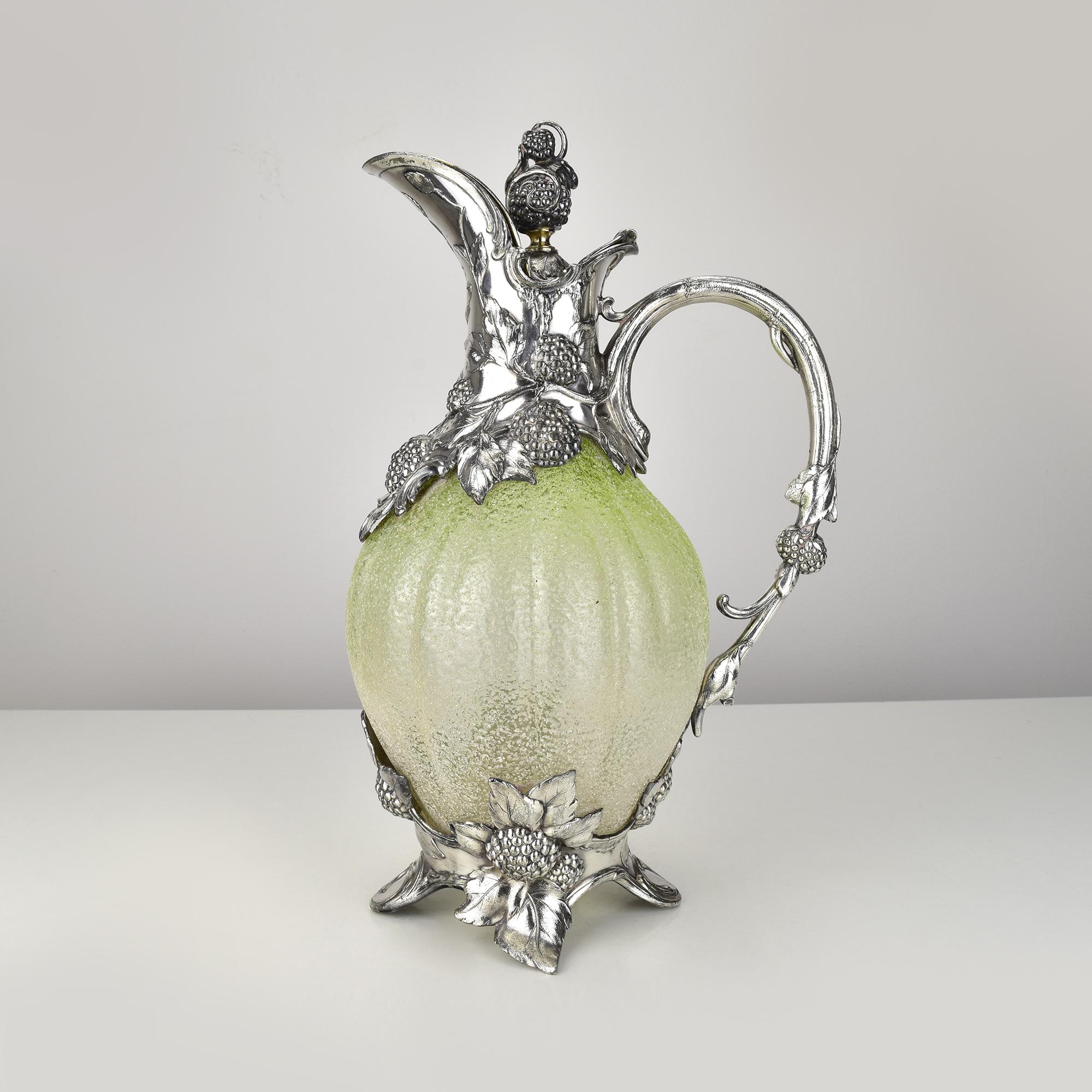 Esta impresionante y rarísima jarra de clarete Art Nouveau de la WMF (Württembergische Metallwarenfabrik) es una obra maestra de la artesanía de principios del siglo XX y data de alrededor de 1900. La jarra presenta un cuerpo de vidrio verde