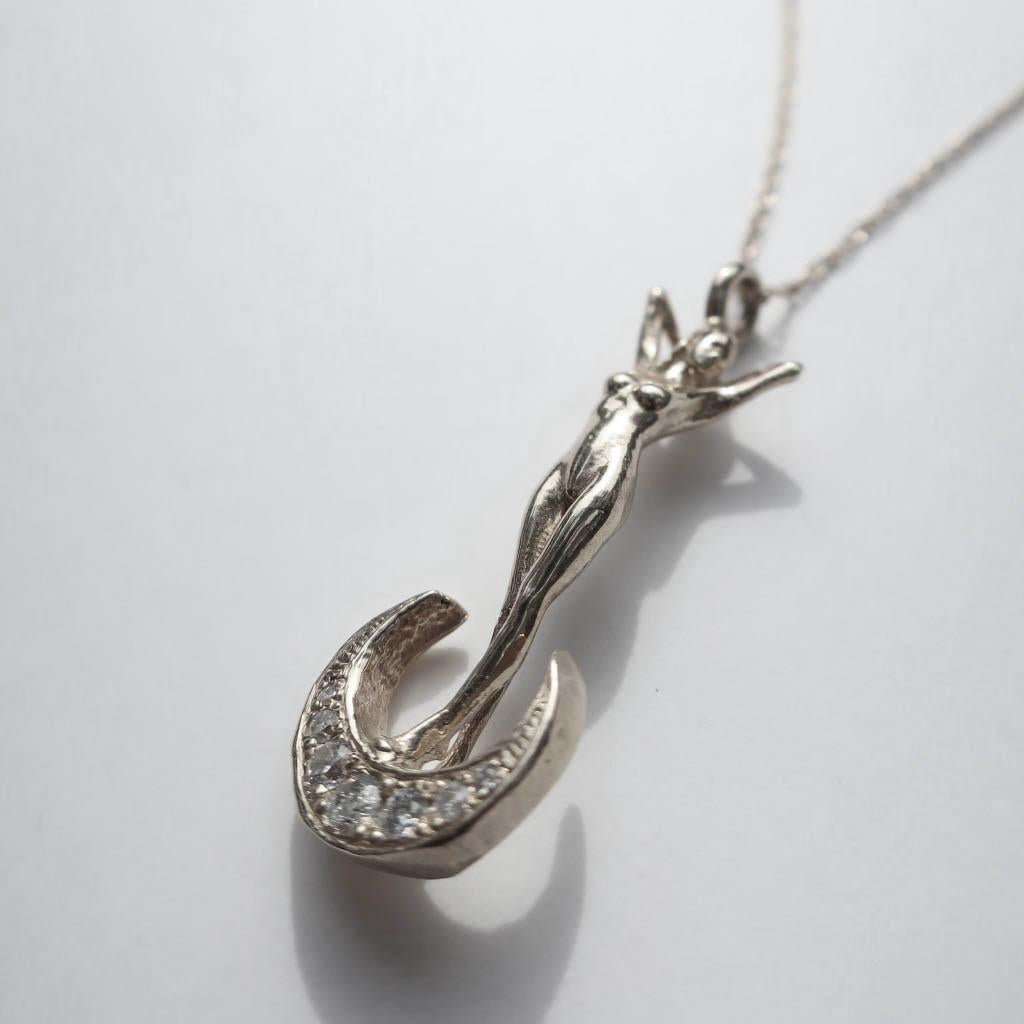Cast in solid 14k white gold this statuesque woman perched atop a crescent moon is a stunning ode to classic art nouveau style themes in jewelry. Strung on a solid 20 inch twisted rope chain this pendant measures 33mm in height.  The moon is bead