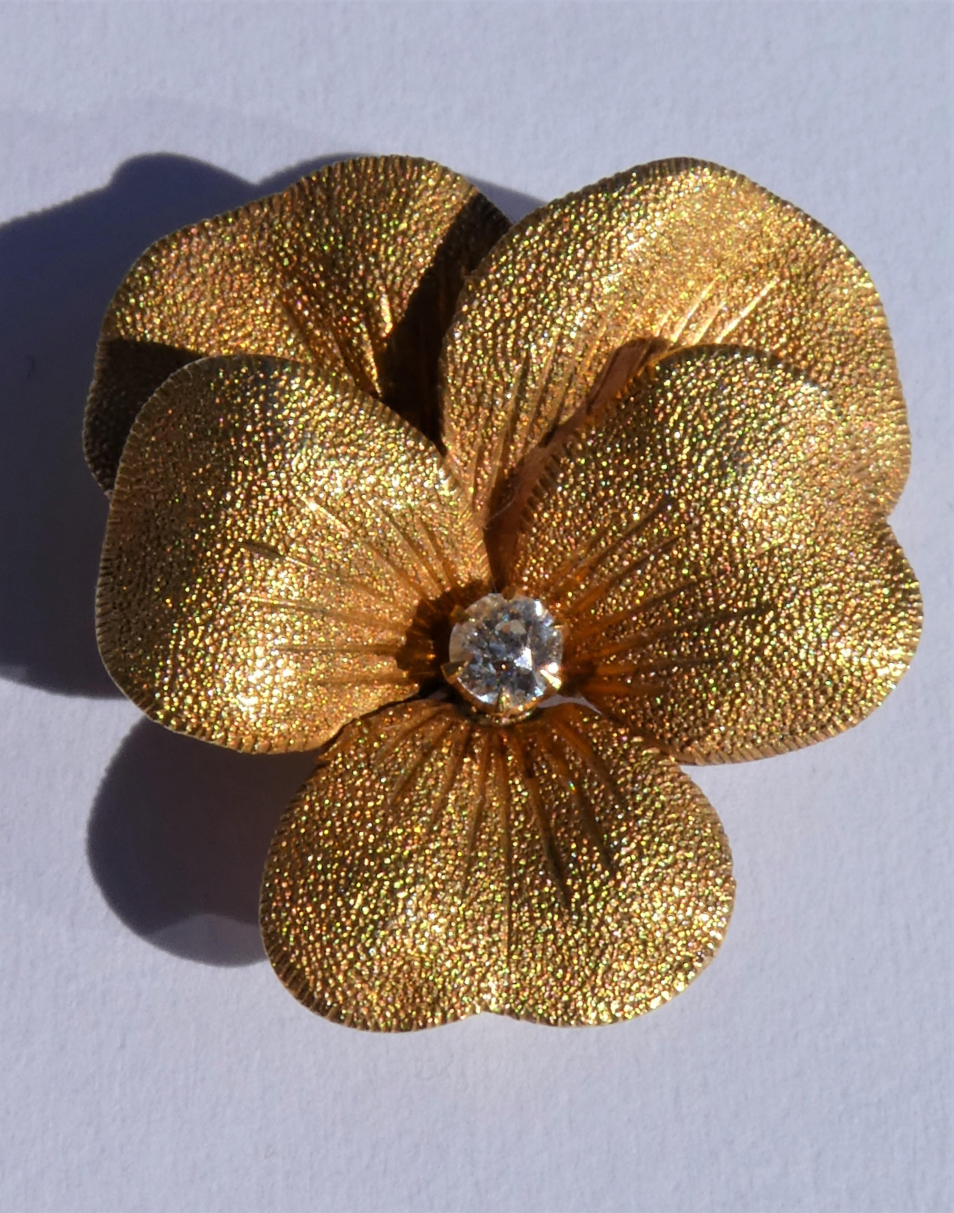 This pretty brooch was crafted circa 1900 in the United States in 14 karat yellow gold. The gold surface is textured and brushed and has a lovely shine. It shows the gold veins in the petals nicely. In the center there is a round old European Cut