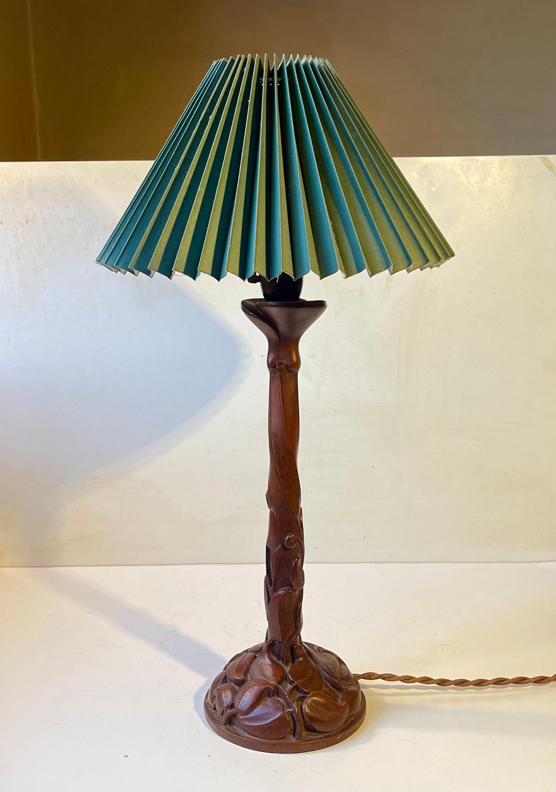 A hand tooled table lamp in solid teak carved with leaves and spiraling details. Its a bespoke and one of unique piece fitted with a brown bakelite socket with practical on/off switch. Its was made in Scandinavia during the 1920s in a mix of