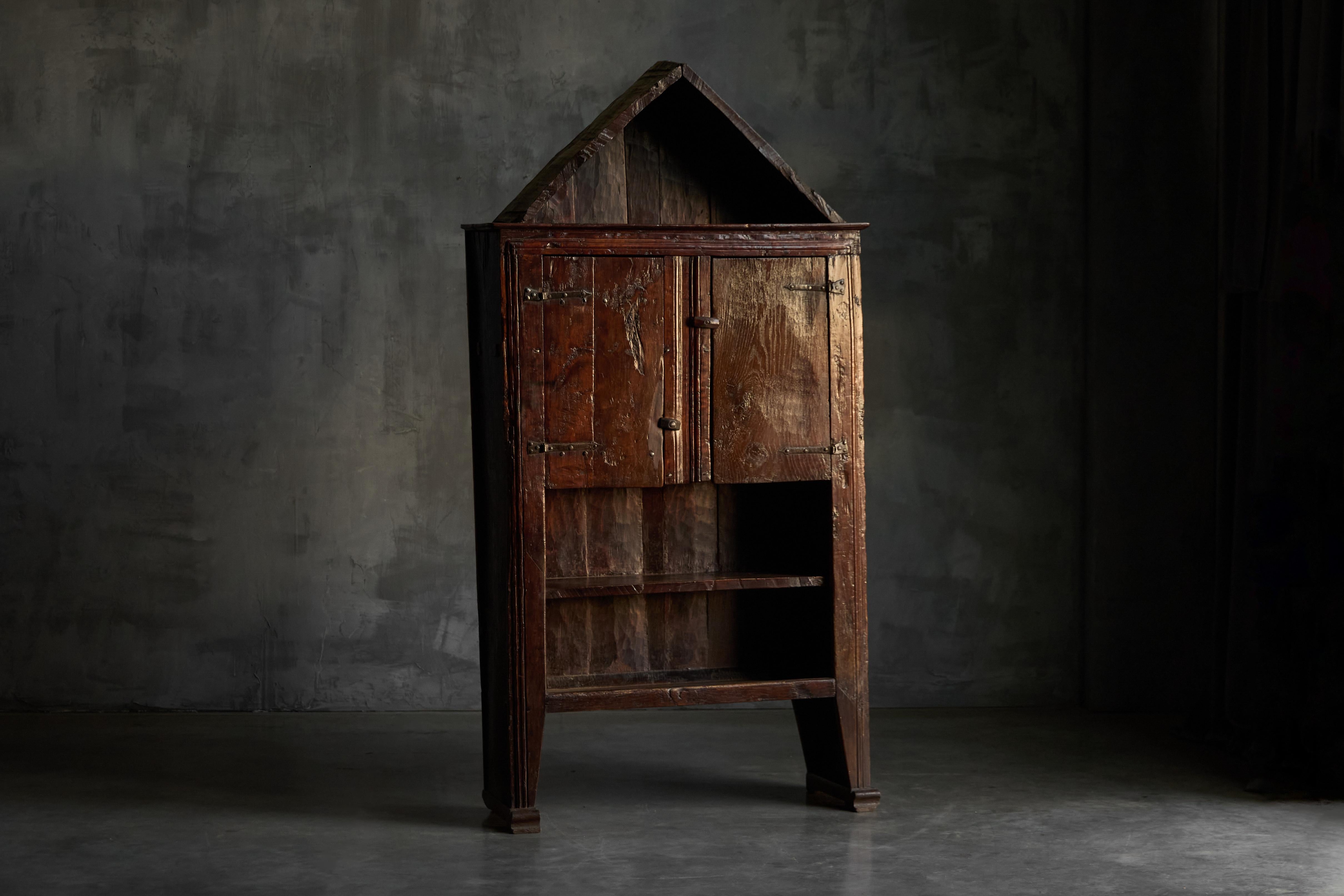Questo affascinante armadio provinciale francese presenta un piano a forma di casa che gli conferisce una stravagante presenza architettonica. Realizzato in legno invecchiato, conserva la ferramenta originale in ferro forgiato a mano e una patina