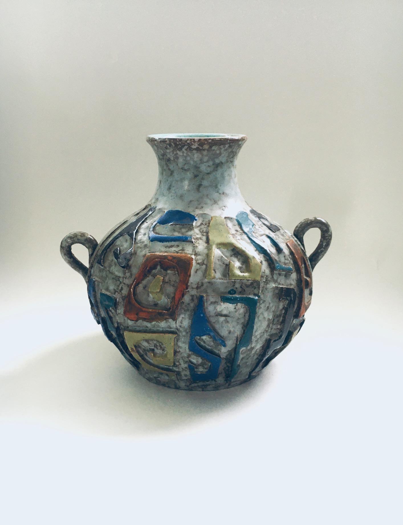 Vintage Midcentury Art Pottery Studio Hand Made Carved Handle Vase. Fabriqué en Espagne, années 1960. Vase artisanal de style brutaliste avec sous-glaçure grise et glaçures bleues, oranges, jaunes verdâtres et brunes. Un vase rare. En très bon état.