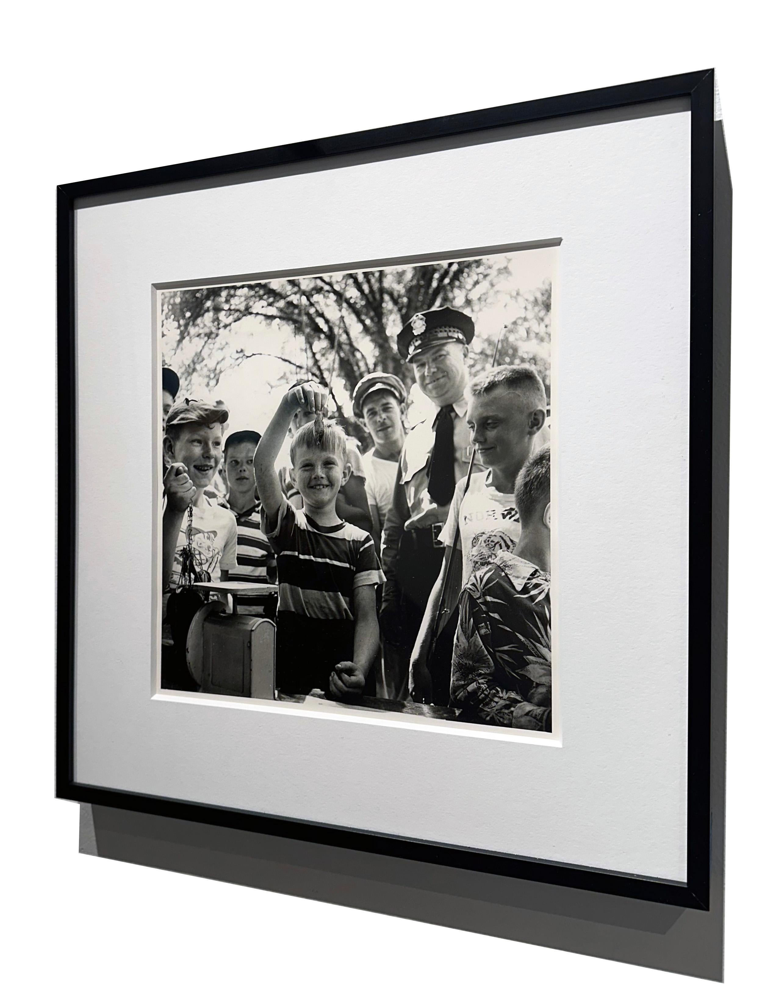 On ne peut s'empêcher de sourire en voyant la joie pure sur le visage de ce jeune garçon qui montre sa prise à un groupe de spectateurs dans la photo d'Art Shay intitulée 