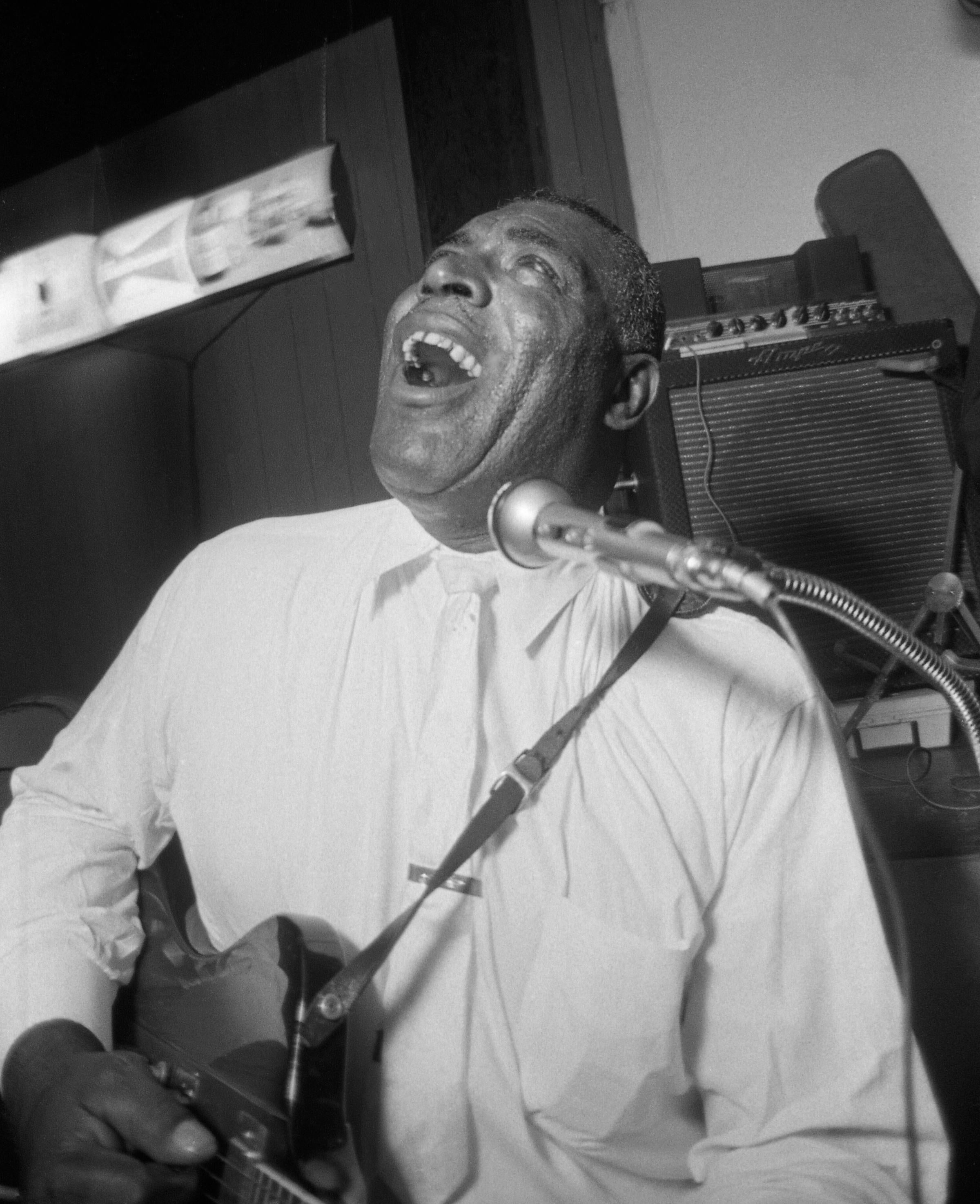 Howlin' Wolf était l'un des grands noms du blues, connu pour son style basé sur la guitare électrique.  Photographiée ici en 1966 par Art Whiting, cette image en noir et blanc est signée dans le coin inférieur droit.  L'œuvre est encadrée et matée,