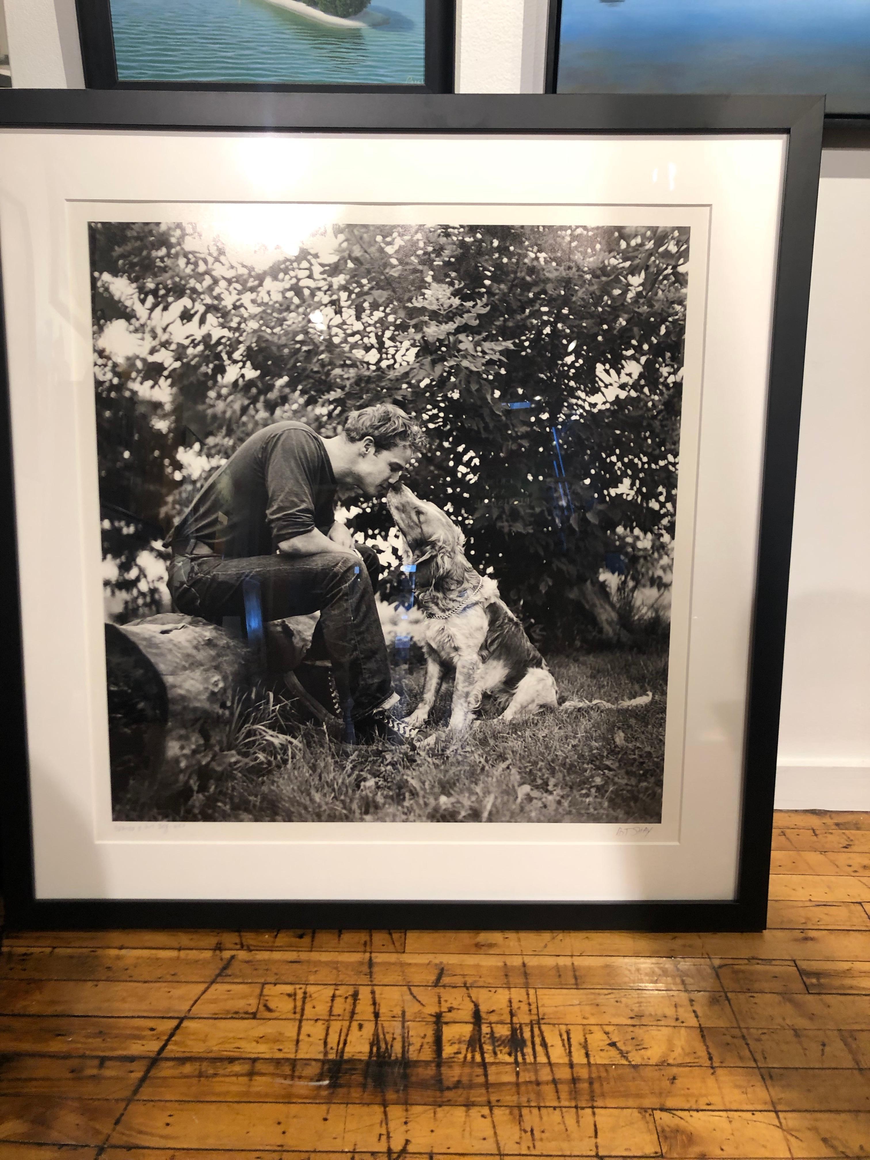 Il s'agit d'une photo en noir et blanc à grande échelle de Marlon Brando, jeune homme, dans la ferme familiale avec son chien.  En 1951, Life Magazine a demandé à Art Shay de photographier Marlon Brando dans sa maison familiale à Libertyville, IL. 