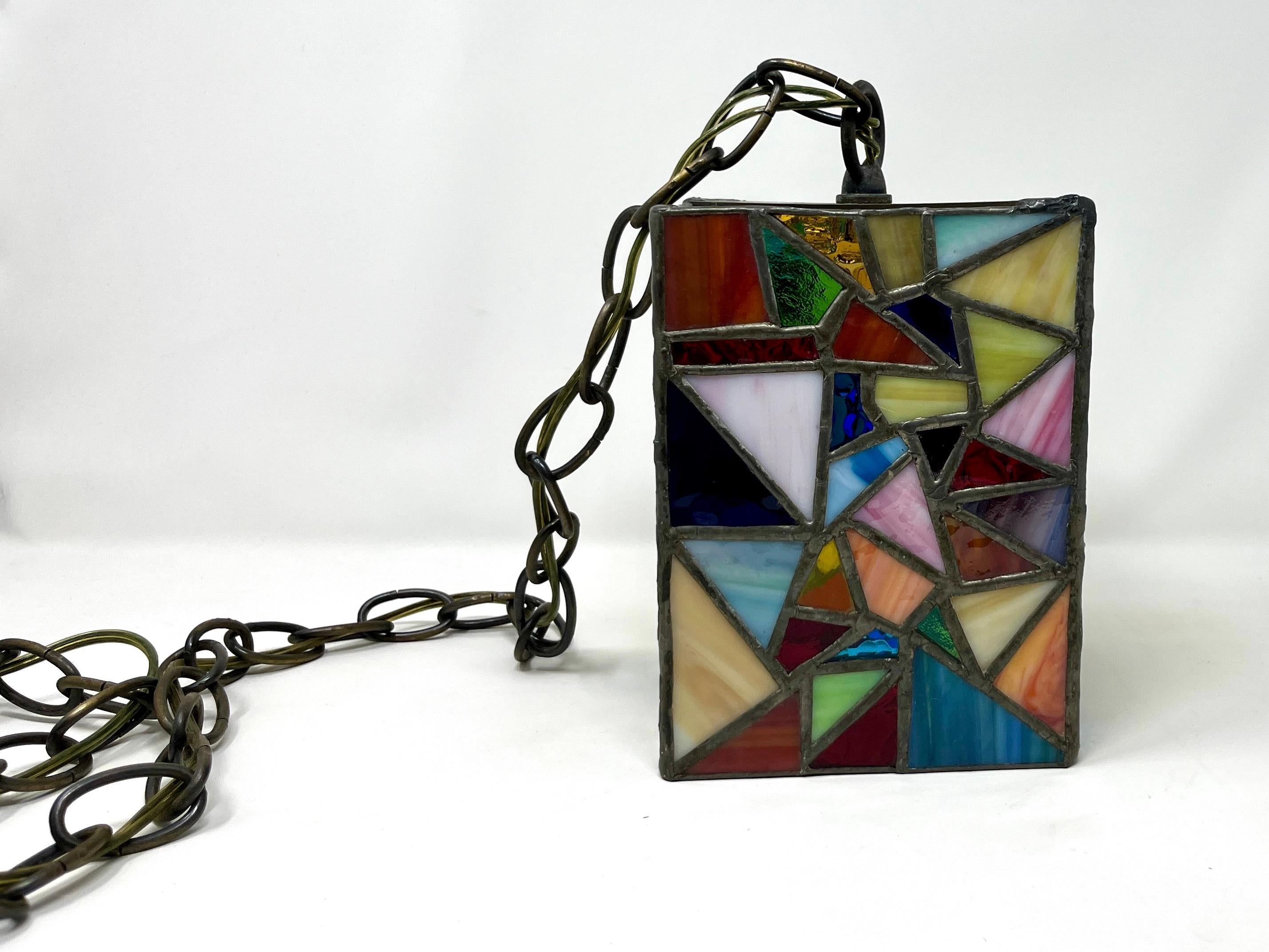 American mid-century handmade stained glass pendant light. A lovely vivid and kaleidoscopic accent light, for a small foyer, hallway, etc. Features a different, unique pattern on each side, made of mostly triangular-shaped, multi-colored pieces of