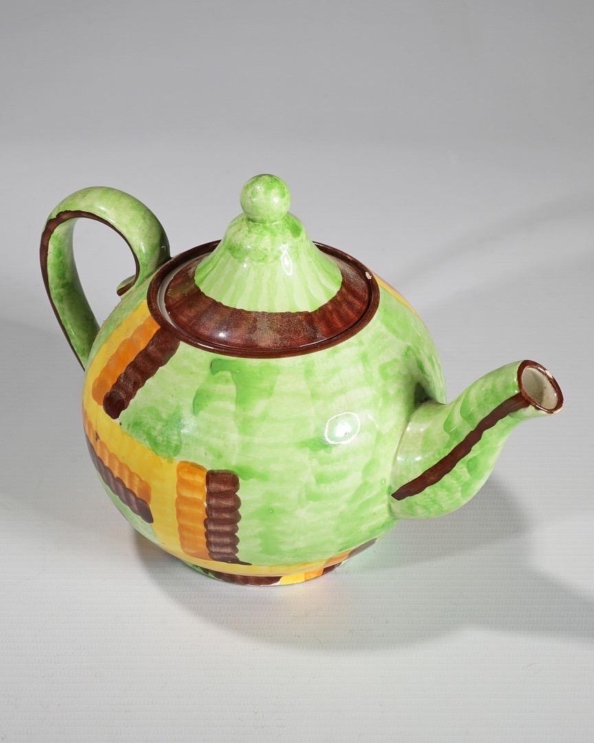 A stunning example of the German Bauhaus design, and a piece of important Zeisel design. Manufactured by Schramberger Majolika-Fabrik. 

The earthenware teapot Hand painted with geometric pattern in yellow, orange and brown on a bright green ground.