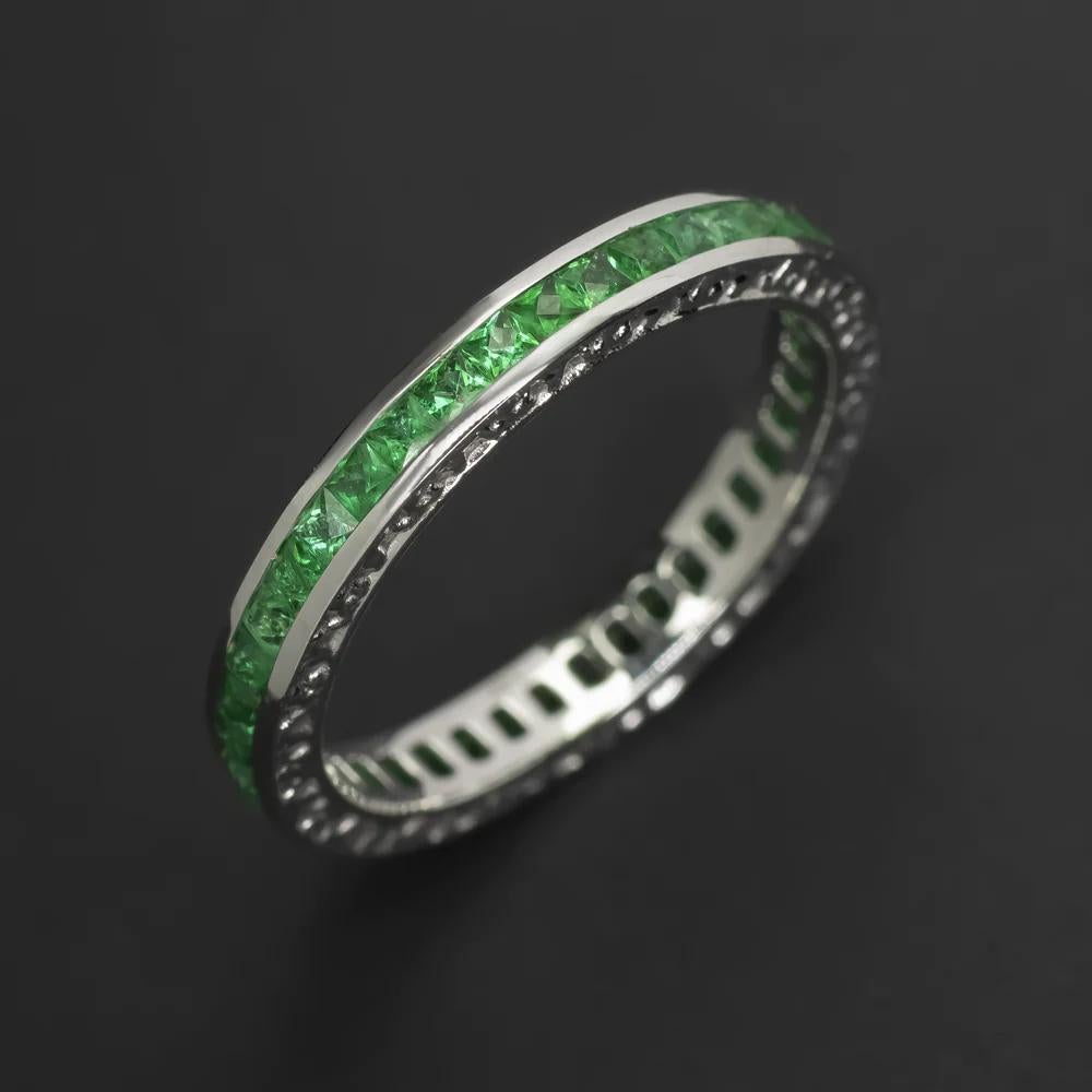 This Art Deco-style emerald eternity band exudes a sleek and sophisticated aesthetic. 

Adorned with 0.80-carat spring green emeralds that catch the light beautifully, it features a French cut design that adds to its vintage romance. The ring boasts