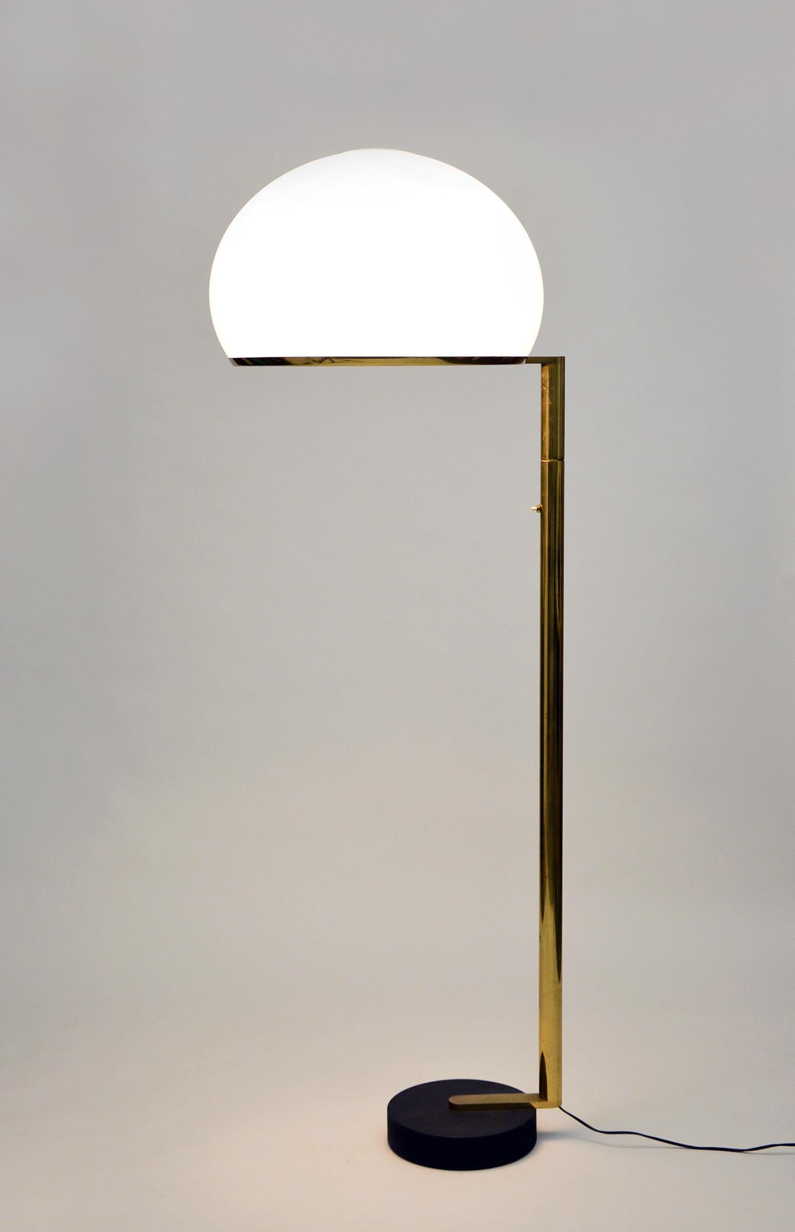 The floor lamp consists of a moulded opal perspex diffuser, a brass stem and a black cast iron base; it can be used both as a reading lamp and, thanks to the opal diffuser, as an ambient light.
The lamp was designed by the