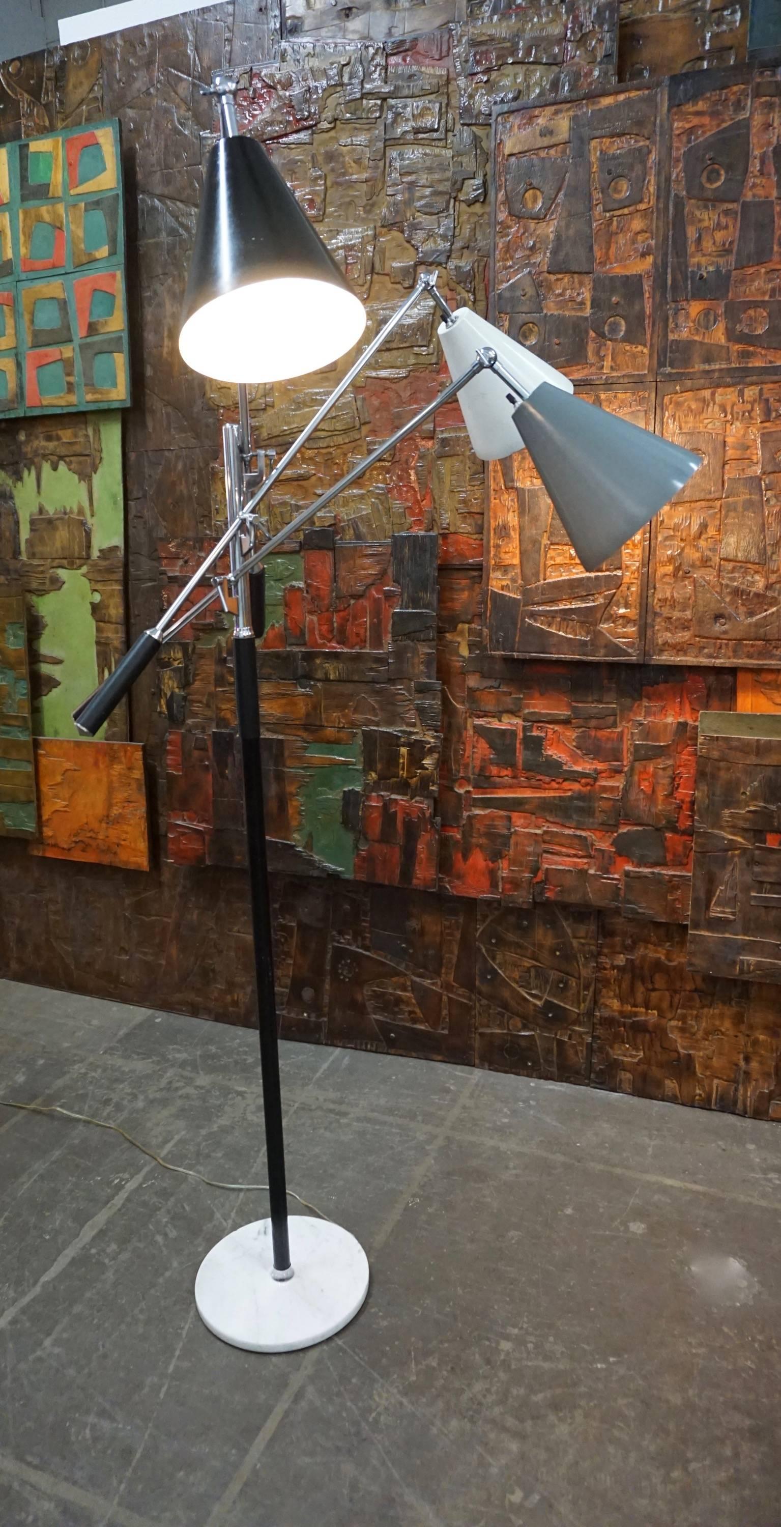 Sculptural three-armed floor lamp in the style of Arredoluce, Italy. A chromed shaft and adjustable, articulating arms with stitched black leather handles and tricolor metal shades; all seated in a round marble base. Stamped “Made in Italy” at the