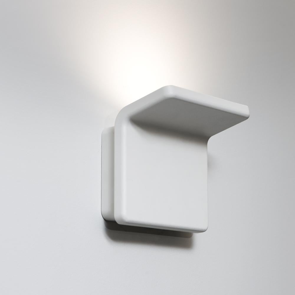 A simple fold of painted aluminum creates harmony between materials, technology and form. Minimal geometry creates space for indirect light. Polished white die-cast aluminum with injection-molded thermoplastic diffuser.

Integrated light source.
