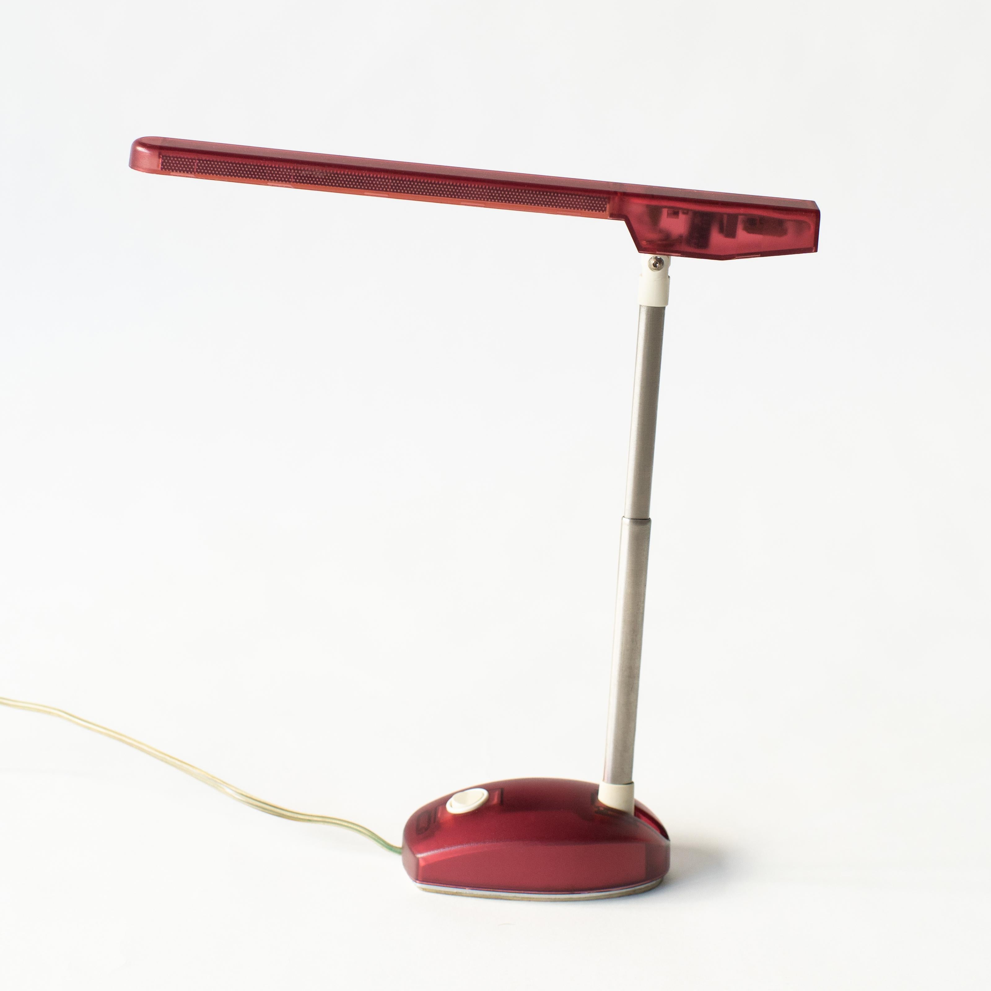 Desk lamp with color half transparent body.  It was released in late 90s by Artemide. It's obvious that it was influenced from first generation iMac released in 1997. Color is red. In those days, there were six color variations. 
It's the style in