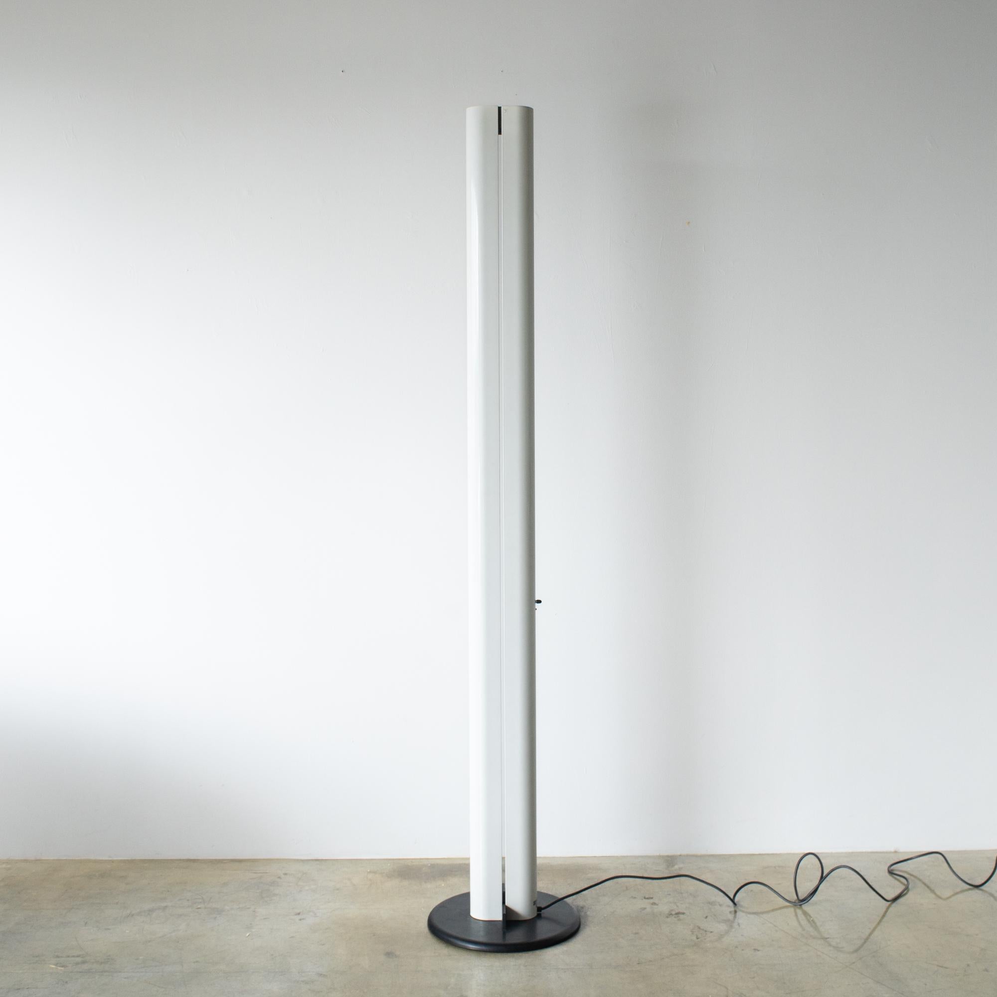 Gianfranco Frattini l'ha disegnata nel 1978 per Artemide. Realizzato in acciaio. Il corpo è bianco, la base è nera. 
Illumina verso l'alto, fino al soffitto, e crea una luce morbida nella stanza.
La sorgente luminosa è alogena r7s da 118 mm.

 