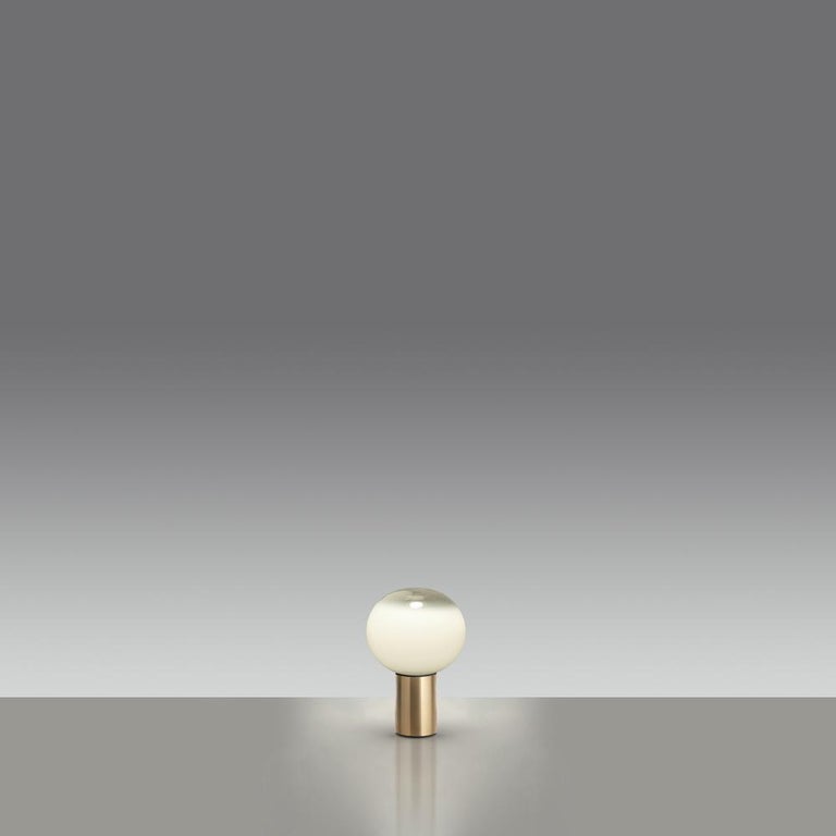 Now available in stunning gold, Laguna table is a spherical table lamp with raised base provides a softly diffused light on the table top and casts a warm light in its surrounding environment. 
This modern and elegant table features hand-blown glass
