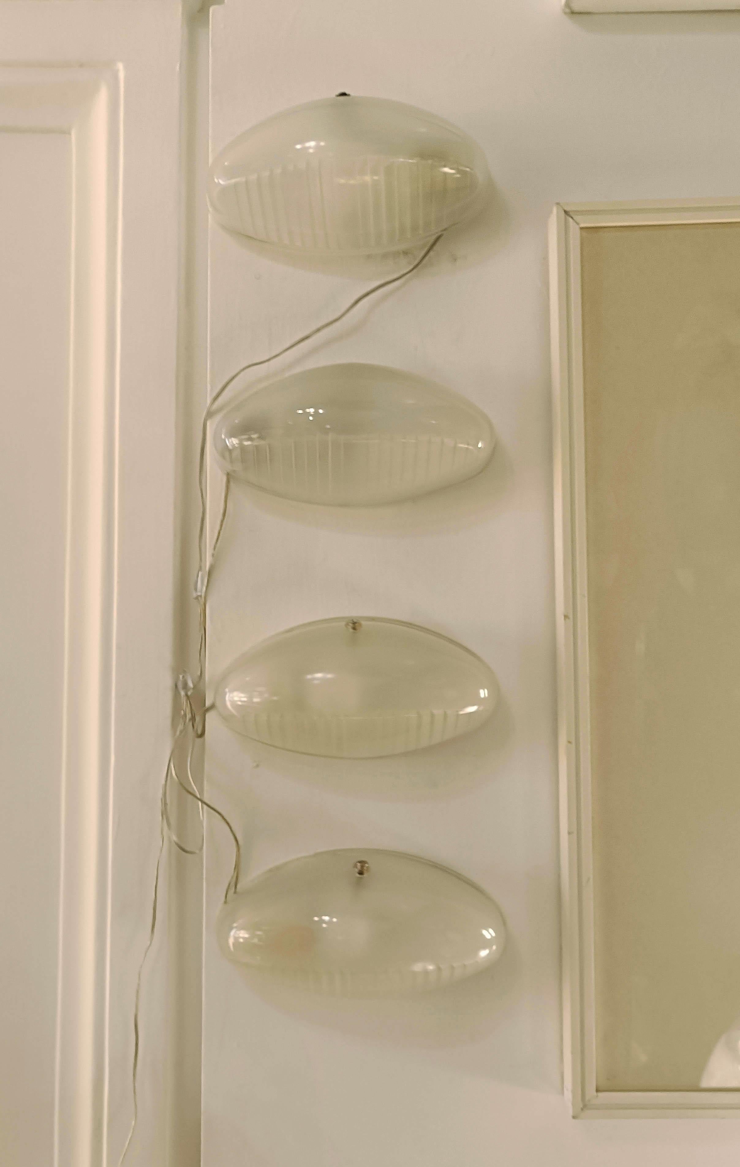 Quattro lampade da parete Artemide negli anni 60. Struttura in metallo e diffusori in vetro sagomato stampato.