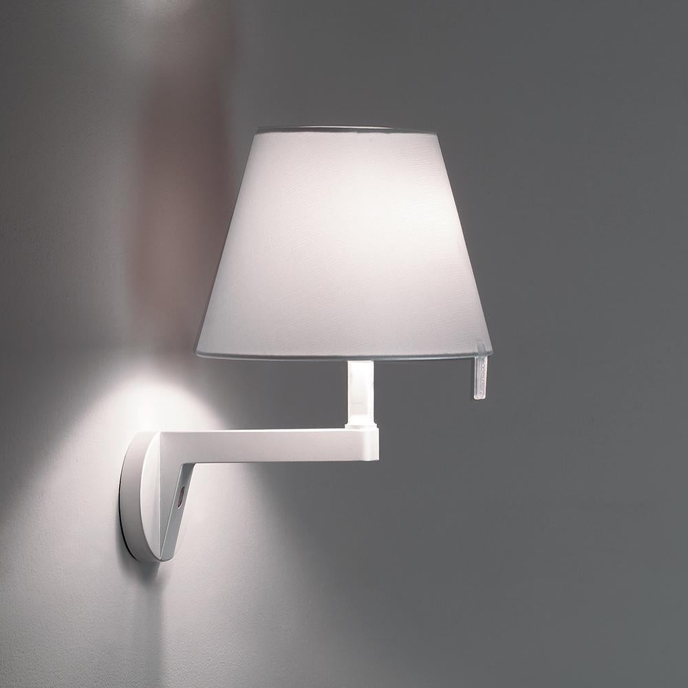 A silk satin fabric shade connected to a painted white zamac base via a painted aluminium stem, Melampo mini can be adjusted for direct and indirect light. 

Melampo Mini accommodates two positions while the standard task lamp can be maneuvered into