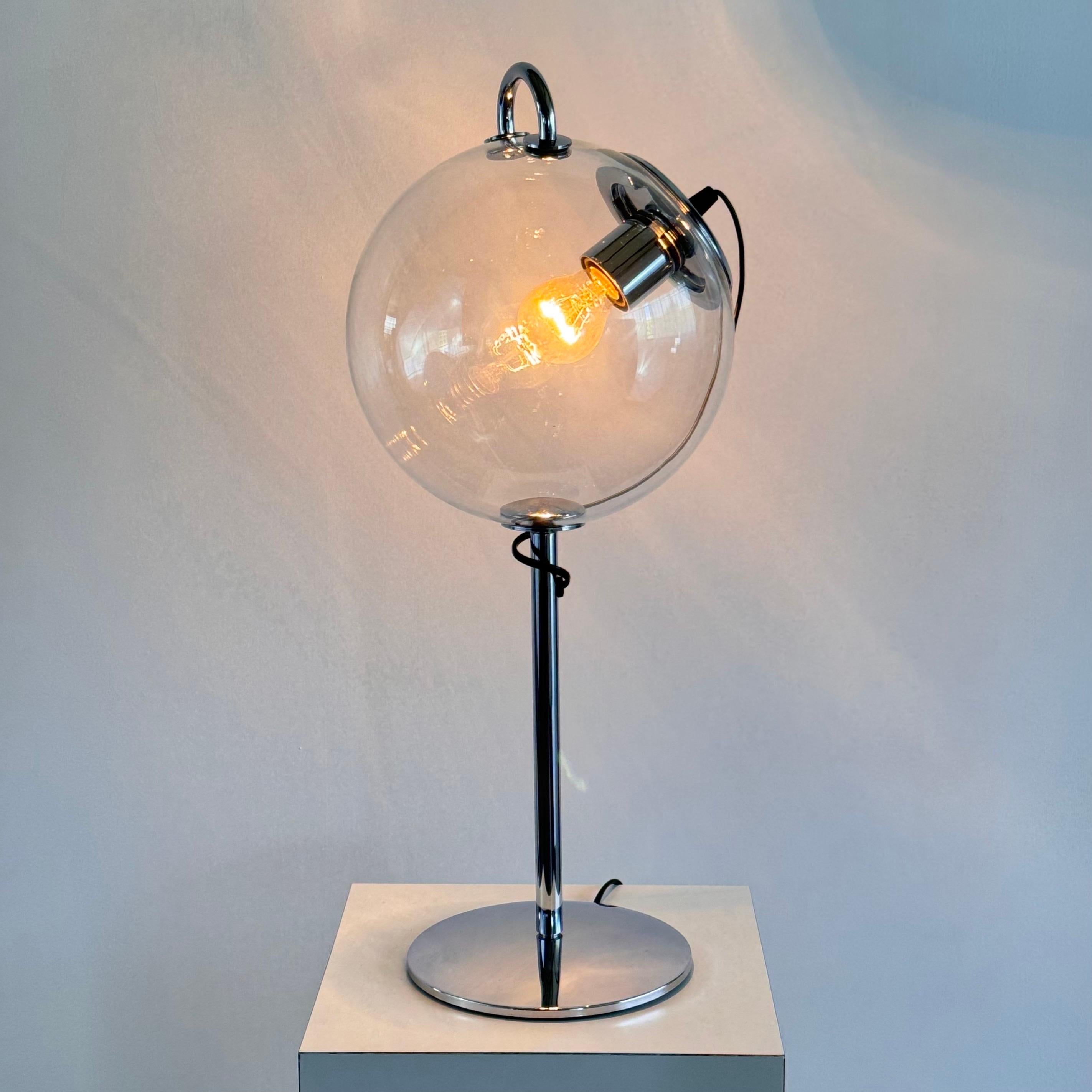 

This exquisite Miconos table lamp, designed by Ernesto Gismondi for Artemide in 1998, exemplifies contemporary elegance with its striking use of materials and form. Featuring a hand-blown glass globe that provides a softly diffused, dimmable
