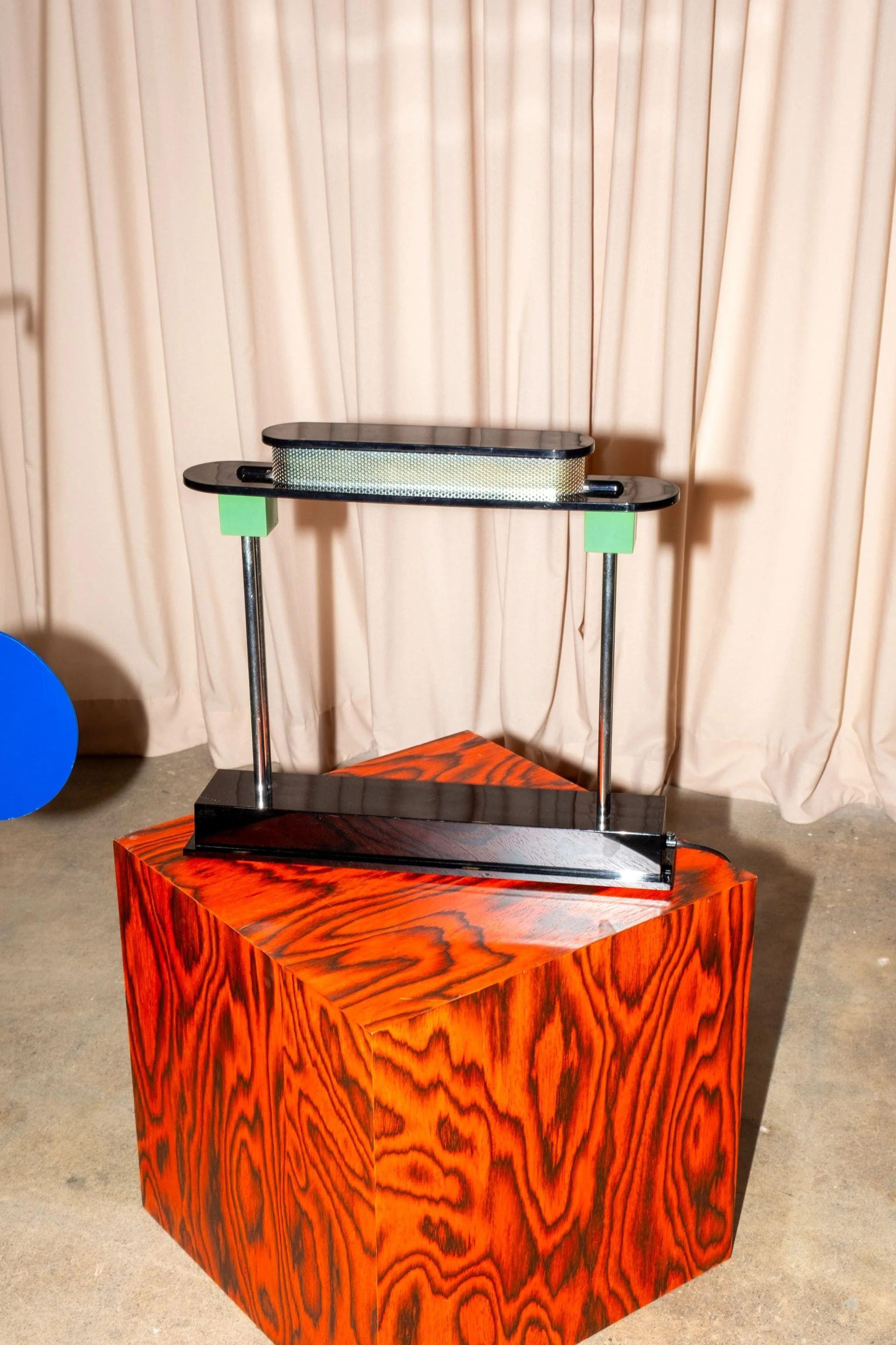 Die Lampe eines Bankiers, neu interpretiert durch eine postmoderne Linse. Die Pausania wurde Anfang der 1980er Jahre von Ettore Sottsass für Artemide entworfen und verbindet klare Geometrie mit verspielten Farben und unverwechselbarer Präsenz. Es