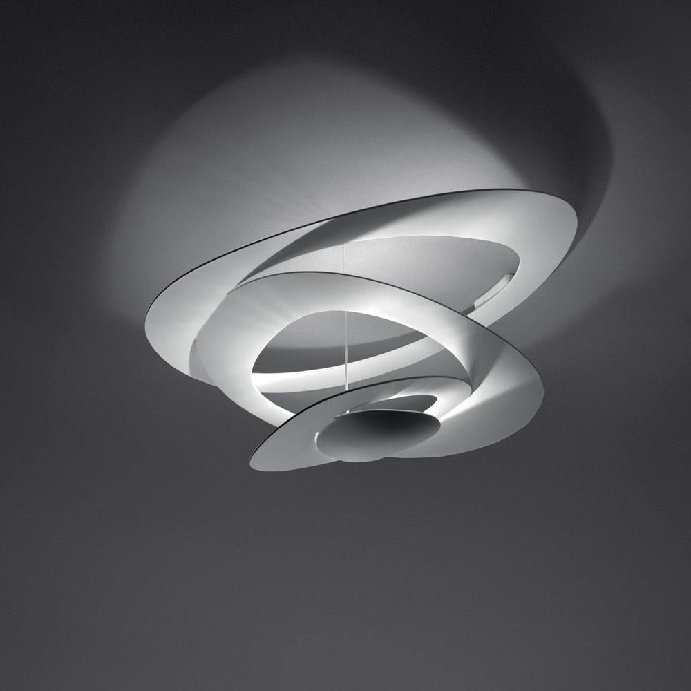 Spirals gently descend delivering sculptural light effects. Painted aluminum body in white or black. 
Body in painted aluminum.
Opening out of a slim disk are fluttering spirals, which fall gently downwards, creating magical effects of form and