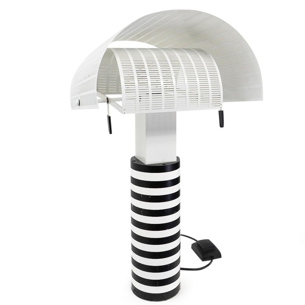 Vintage Table Lamp, model Shogun, designed by the architect Mario Botta for Artemide (1985).

An impressive lamp being a typical design originating from the Memphis-Milano movement.

Materials: Powder coated cast-iron base. The metal cylindrical