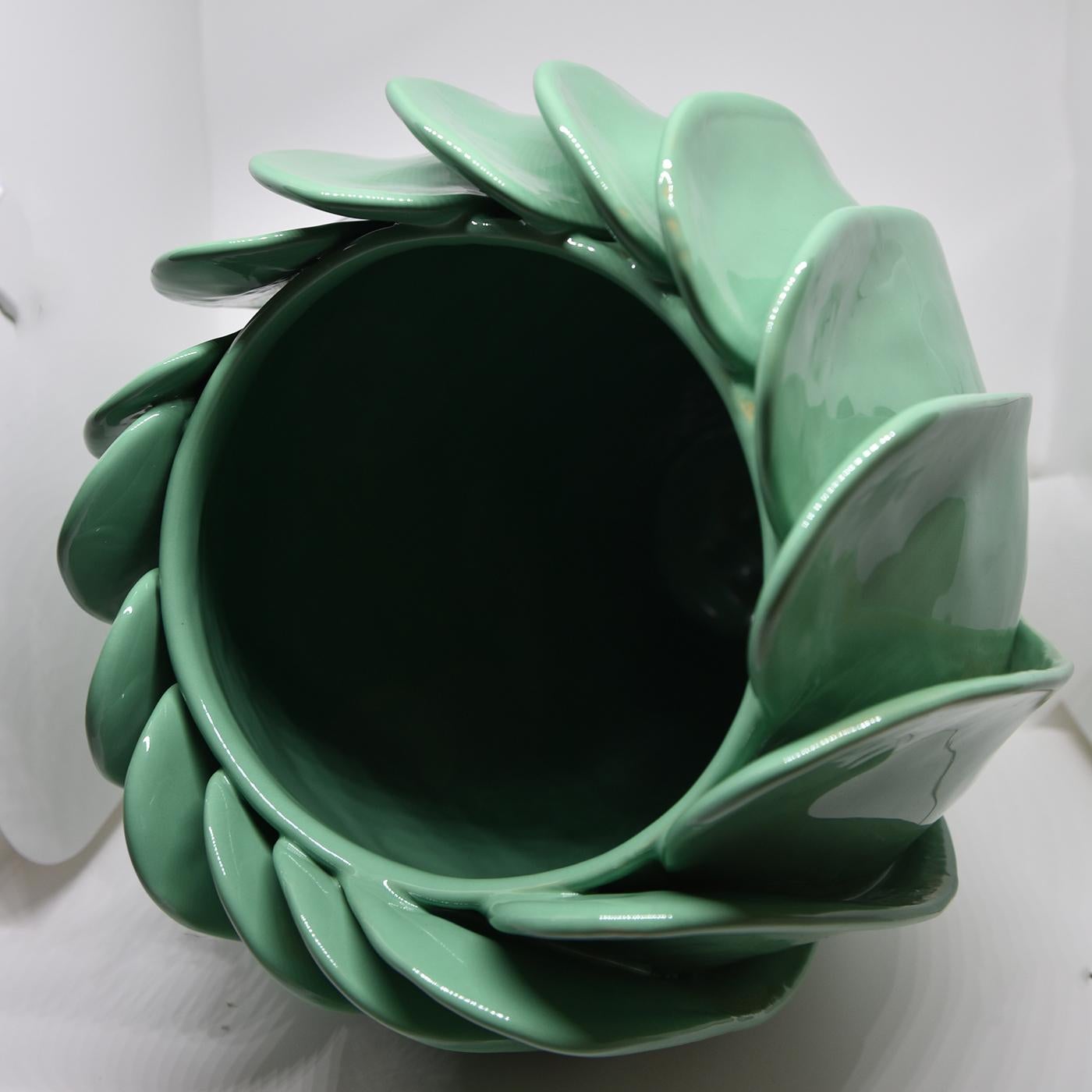 This remarkable vase is part of a limited series of numbered pieces all signed by the artist. This piece features a glossy aqua-green glaze and a truly captivating shape resembling the petals of a flower that is about to bloom. Because it is made by