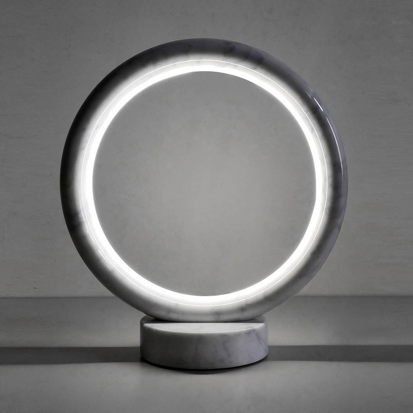 This striking table lamp was designed by Joe Gentile and Fabio Crippa of Studio ADL. The Minimalist lines of the piece use the circle as main element, for both base and shade. The sinuous silhouette of the frame envelops the LED light and is made