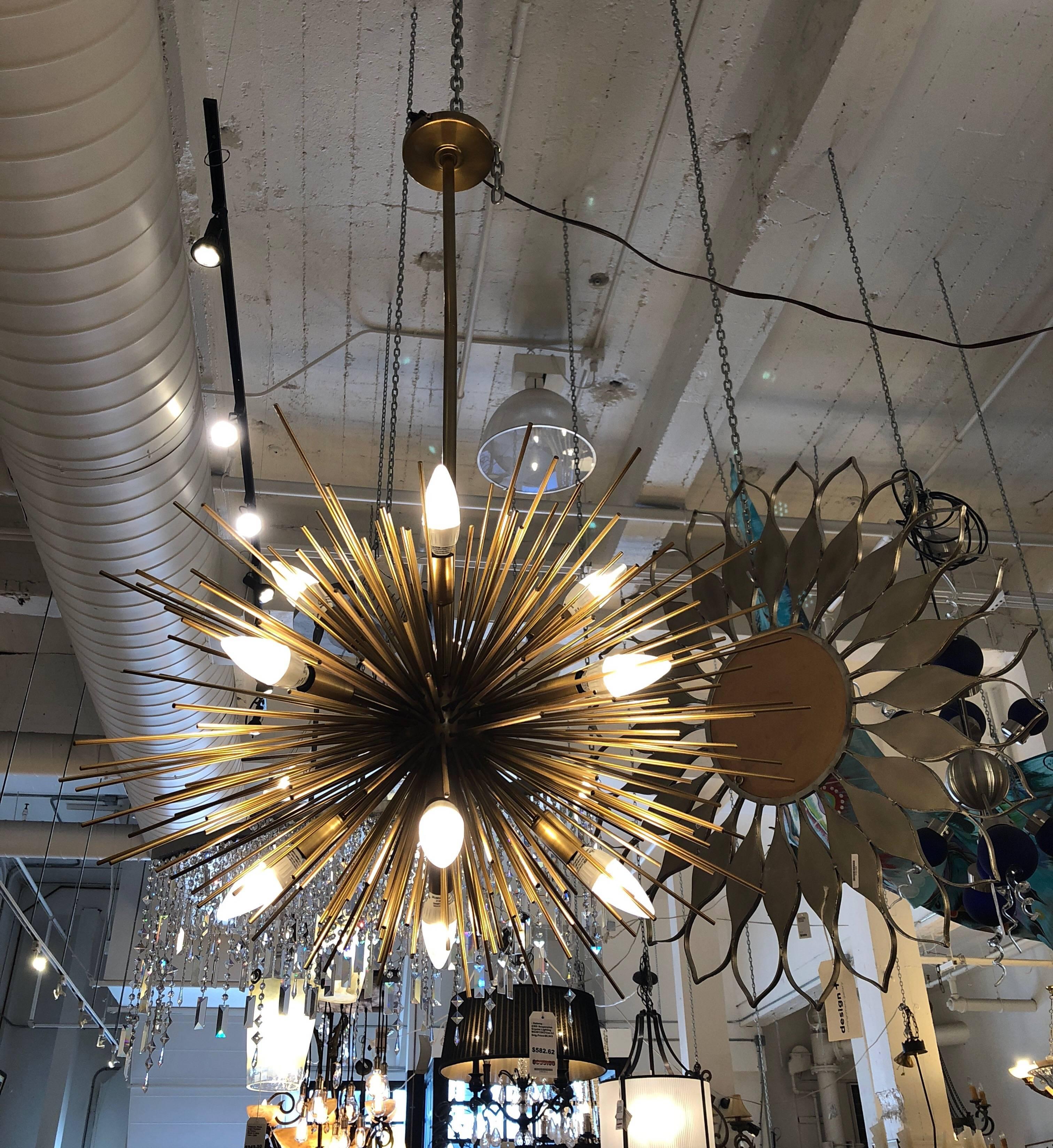 A Zanadoo chandelier by Arteriors. A modern take of retro flair. A midcentury aesthetics combines an explosion of shiny spokes with modern exposed bulbs that cast arrays of light. 12 40 Watt bulbs. The finish is antiqued brass.
 