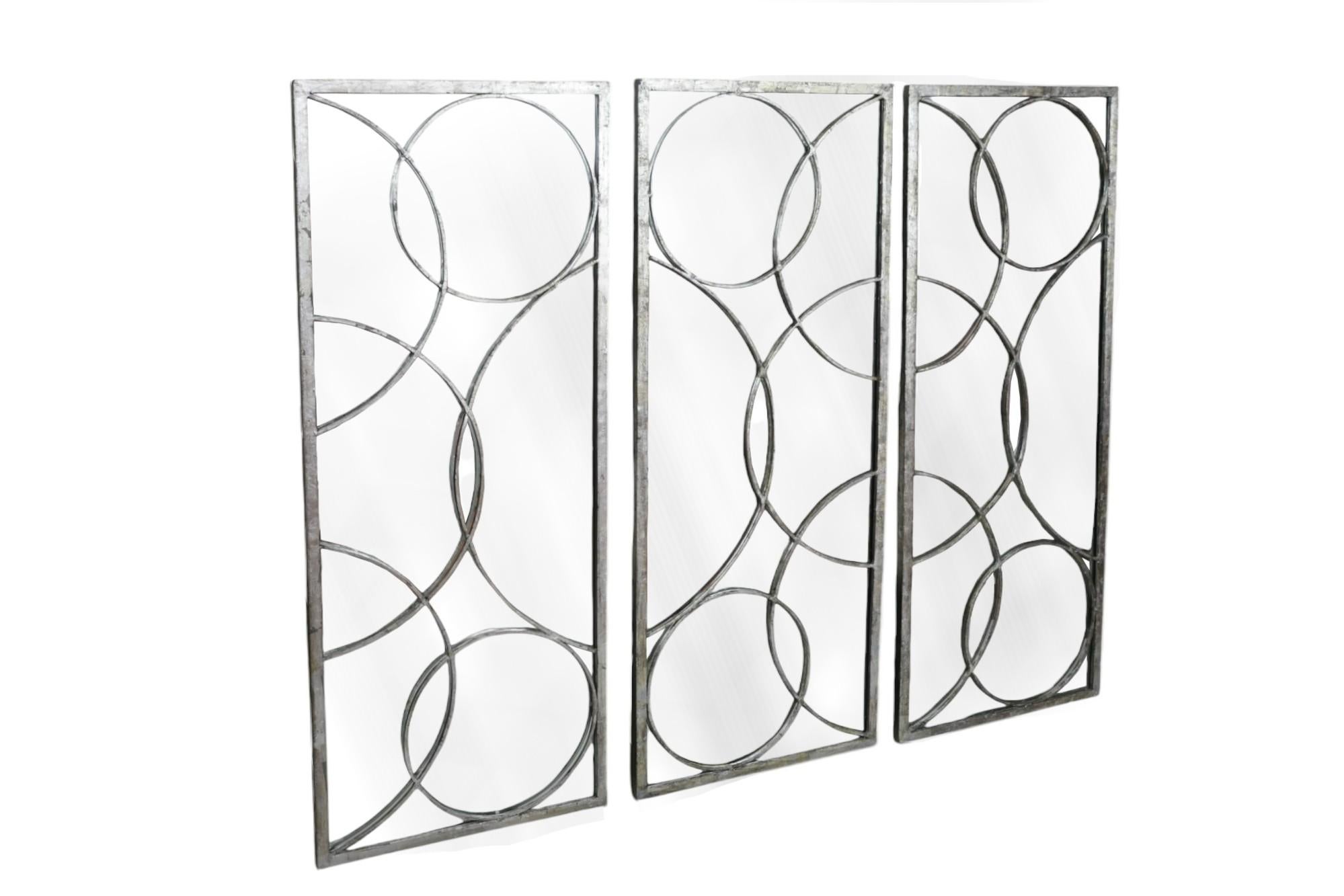 Ensemble de trois miroirs contemporains 'Nikita' par Arteriors Home. Les cadres rectangulaires sont décorés de cercles superposés en fer forgé à la feuille d'argent. Le Label du fabricant est visible à l'arrière. Dimensions par miroir.