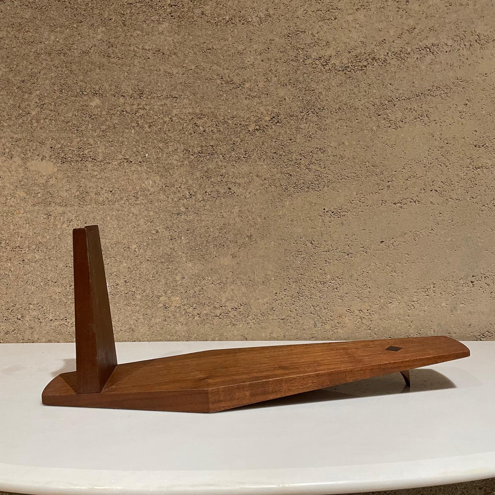 Artsy Bottle Holder
Artful modernist solid wood wine bottle cradle holder stand studio piece 1960s California Craft.
Unmarked
Made of solid wood in exotic Rosewood and Walnut. 
Measures: 6.5 tall x 16 L x 4.5 W inches
Refer to images.
Original