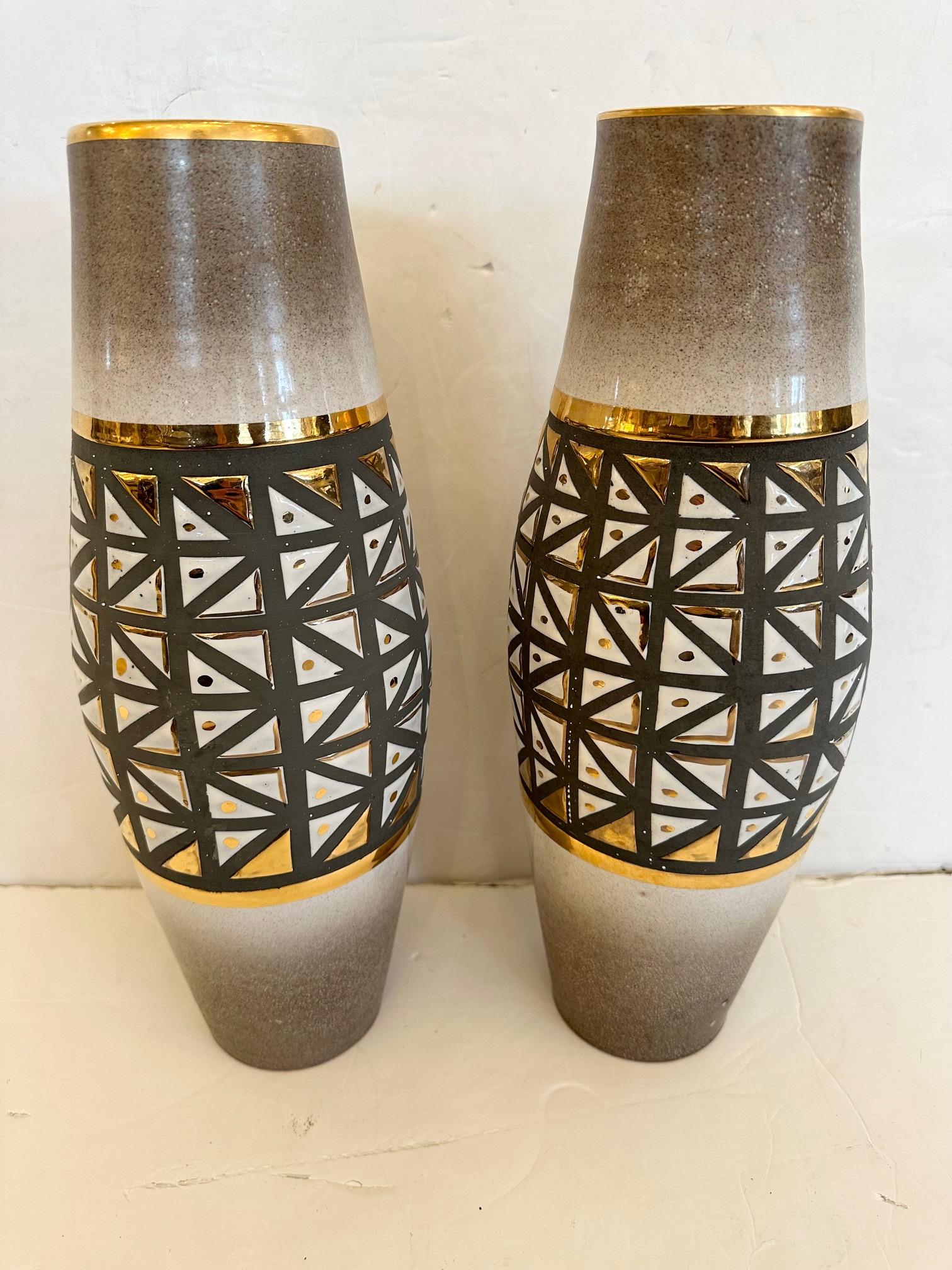 Beautiful pair of hand crafted midcentury modern pottery vases having gray & white geometric shapes with gold gilding accents.