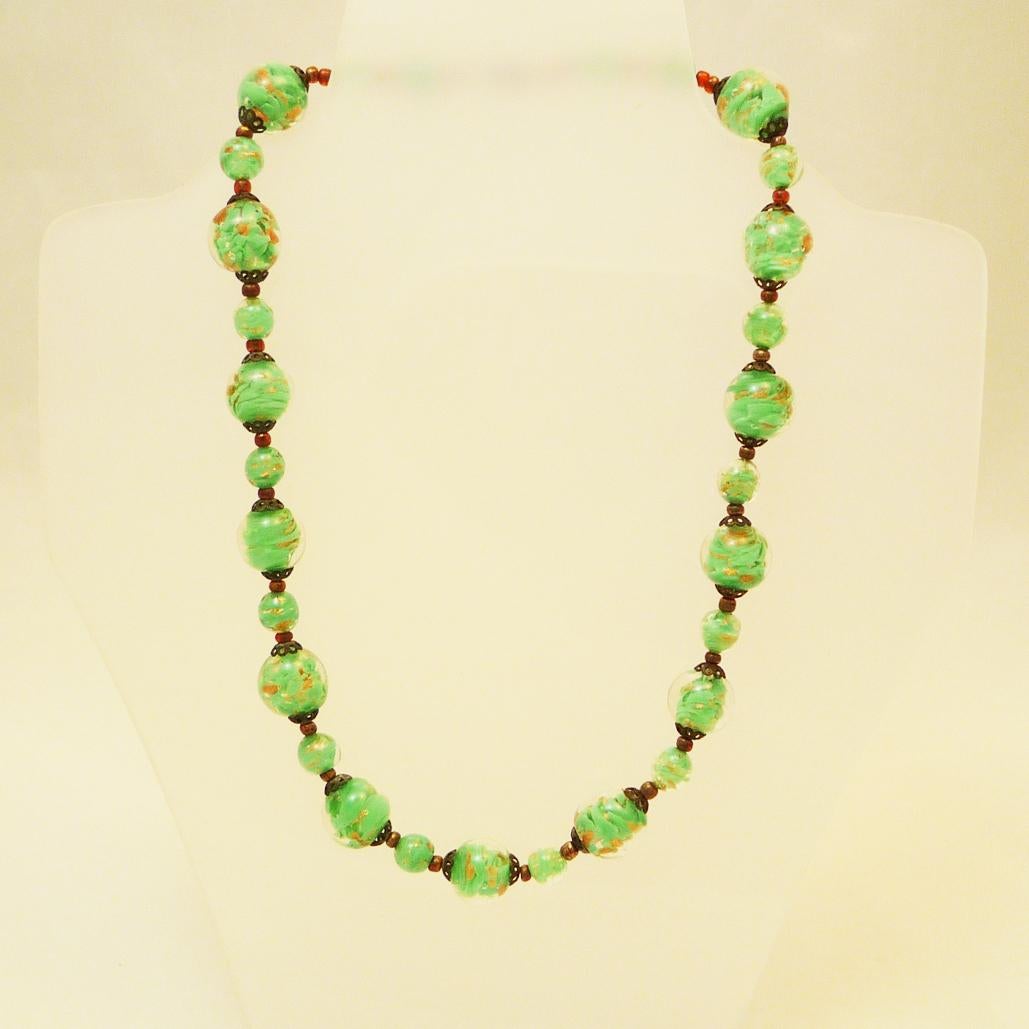 Kunstglas-Halskette Murano-Perlen mit Goldfluss, in leuchtendem Grün

kunstvoll gearbeitete Glaskugeln mit goldenen Fließelementen

Länge der Kette: 47 cm

Durchmesser der Kugeln: 9-15 mm

um 1930