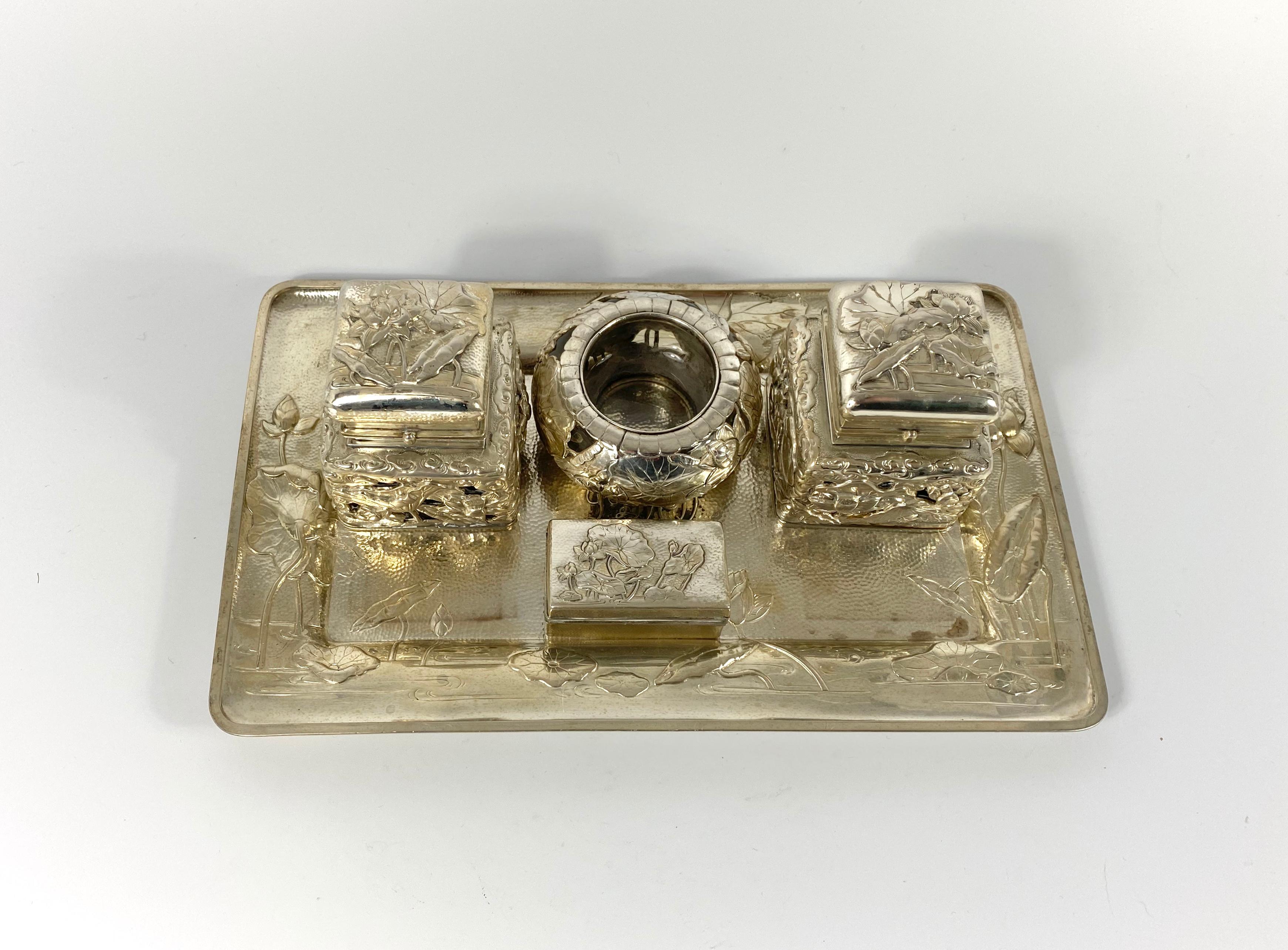 A fine and rare Arthur and Bond of Yokohama, silver inkstand, circa 1900. Meiji Period. The rectangular silver tray, chased and embossed with flowering lily pads on a river. Twin silver mounted glass inkwells; the pierced silver again decorated with
