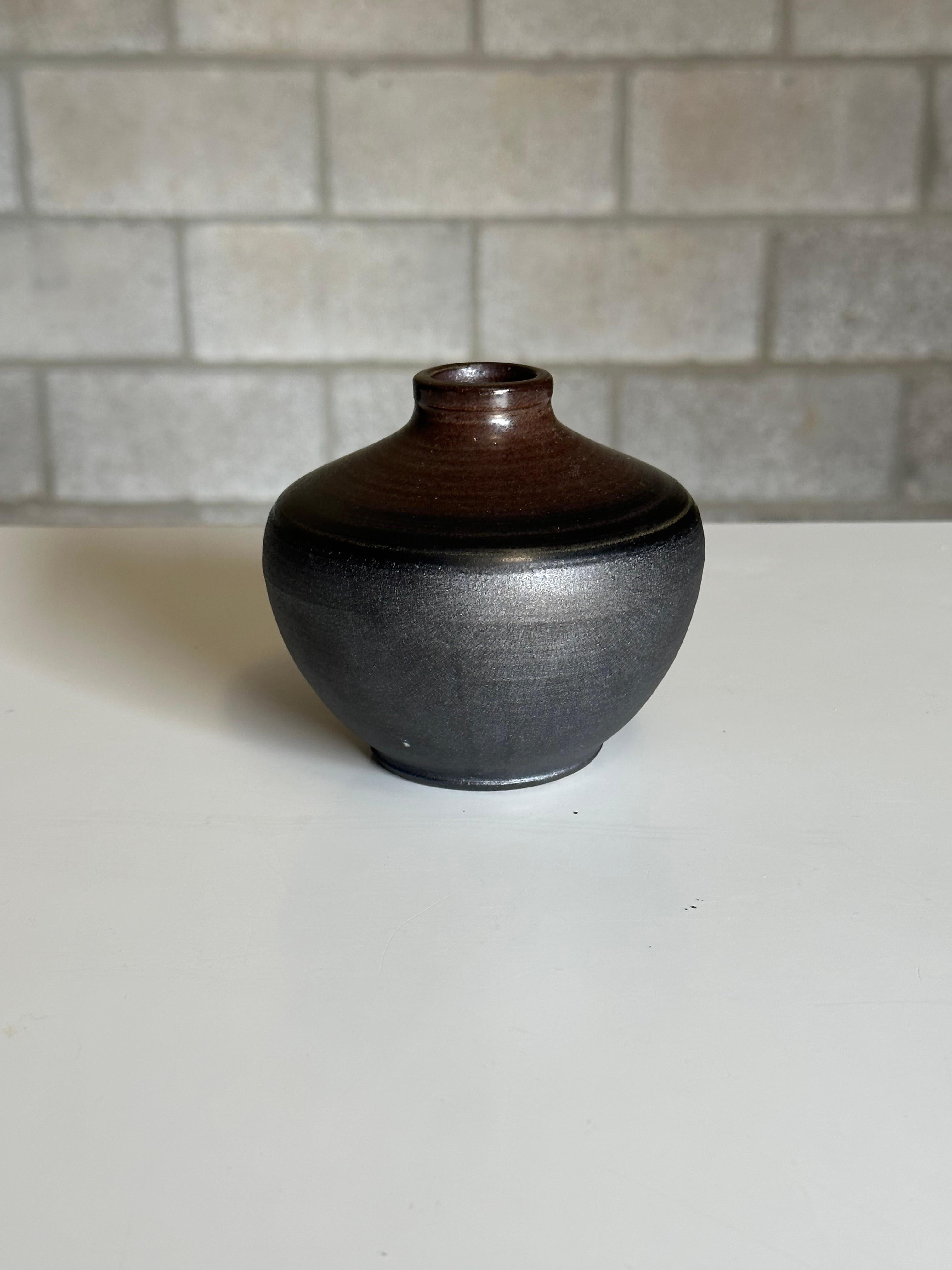 A stoneware vase designed by Arthur Andersson for Wallåkra, circa 1950s. Features an exciting glaze which starts as a rough flat black towards the bottom and moves into a glazed black with some dark brown near rim. Very heavy well made piece