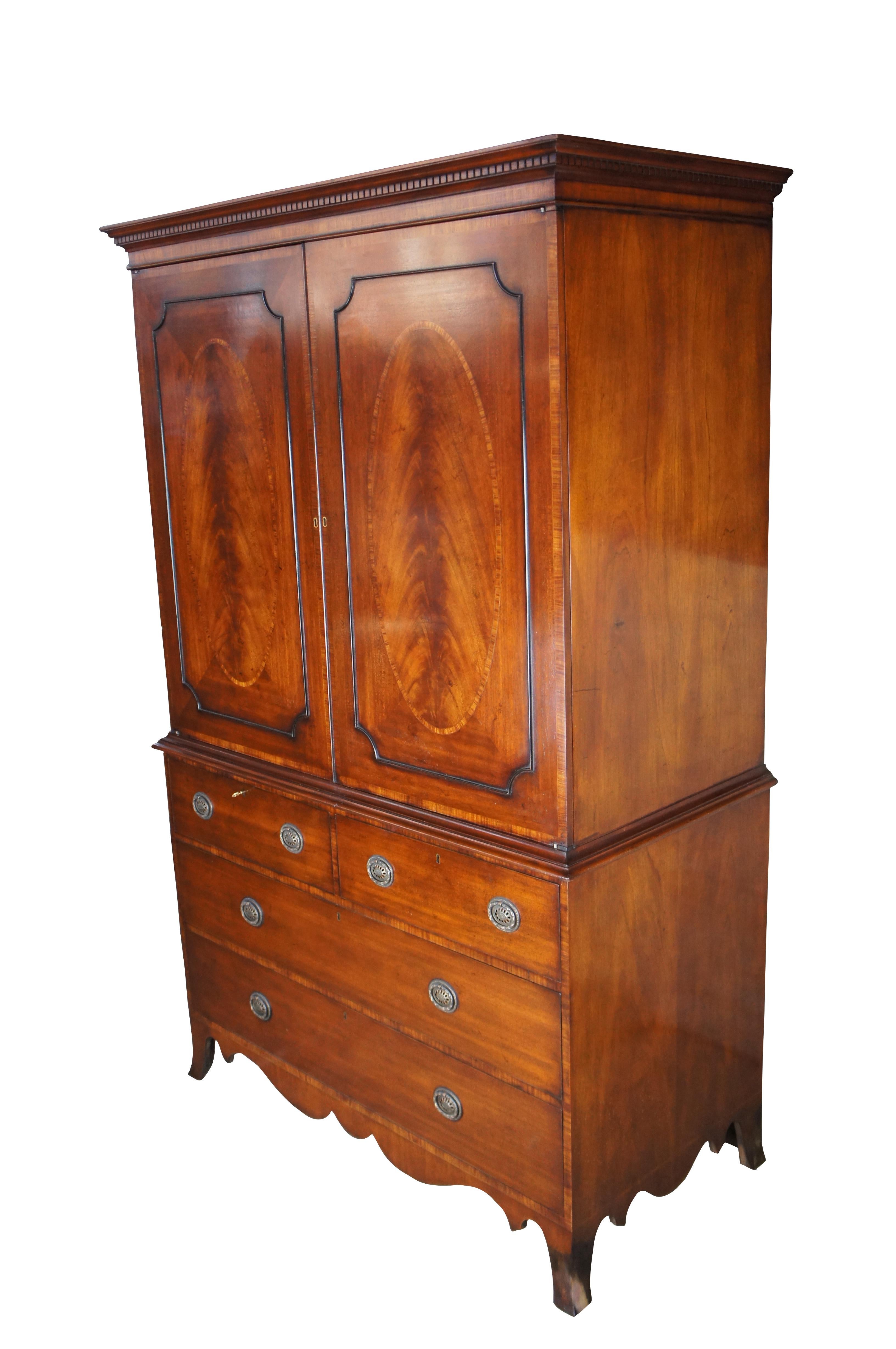 Late 20th Century George III Armoire by the English Cabinetmaker Arthur Brett. A two piece case made from mahogany with panels of crotch mahogany, cross banding and inlay. The upper portion showcases beautiful flame mahogany doors, oval
