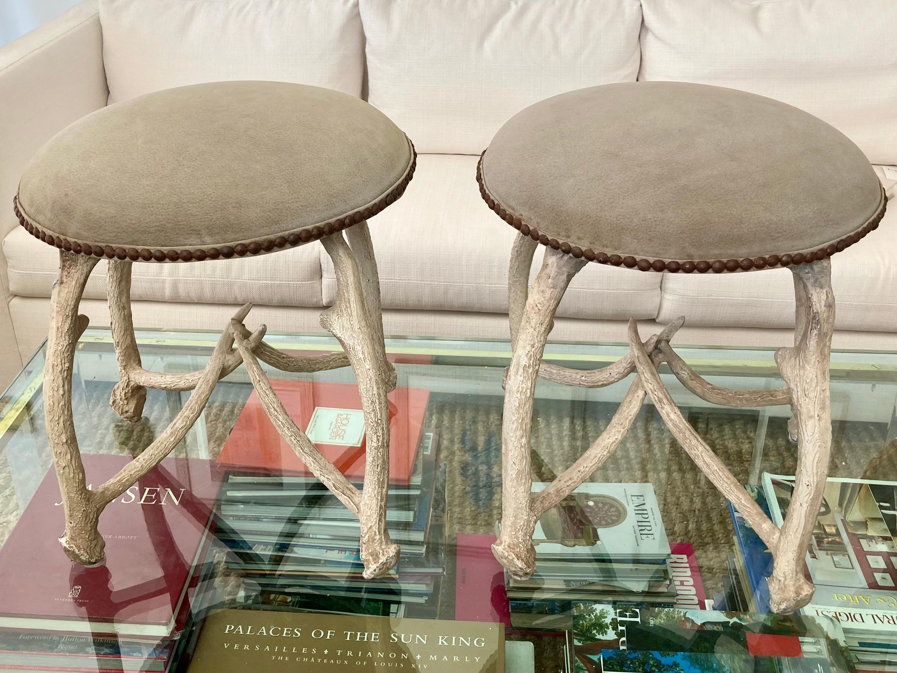 Beautiful pair of Arthur Court horn ottomans. These are cast aluminum with a hand painted off-white natural finish. Classic light gray suede upholstery. Vintage items with some wear, but adds the character.