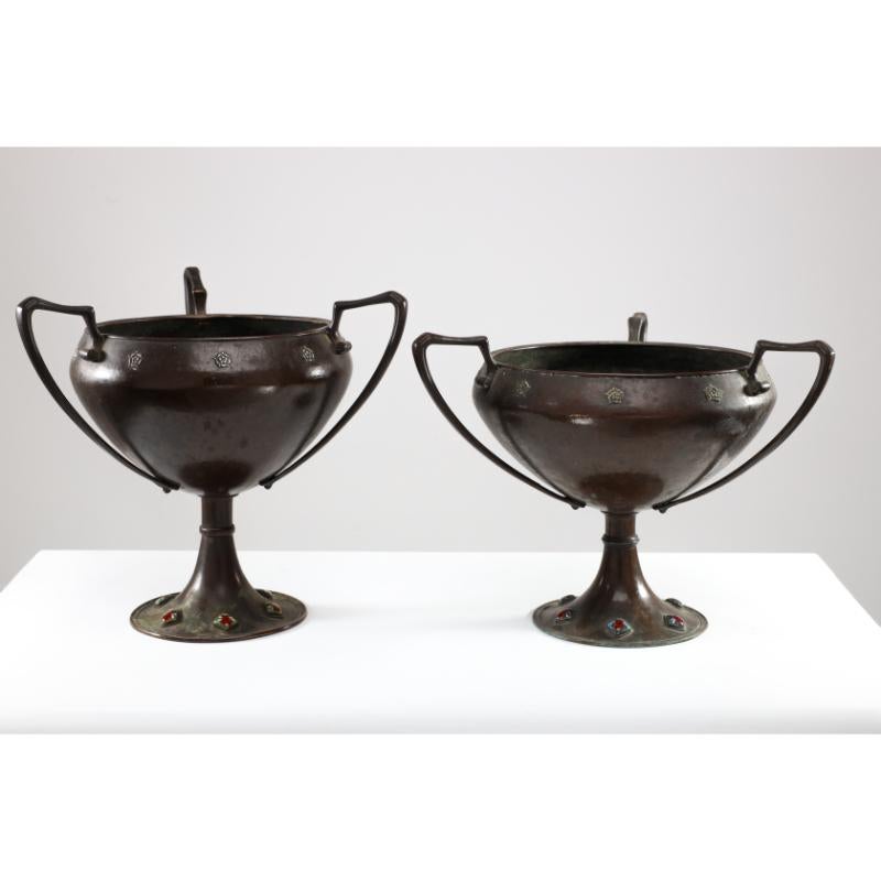 Arthur Dixon for the Birmingham Guild of Handicraft. Two Arts and Crafts hand-hammered copper centre pieces both with three handles and little scroll details to each side of each handle where they meet the upper bowl, and a feather style detail to