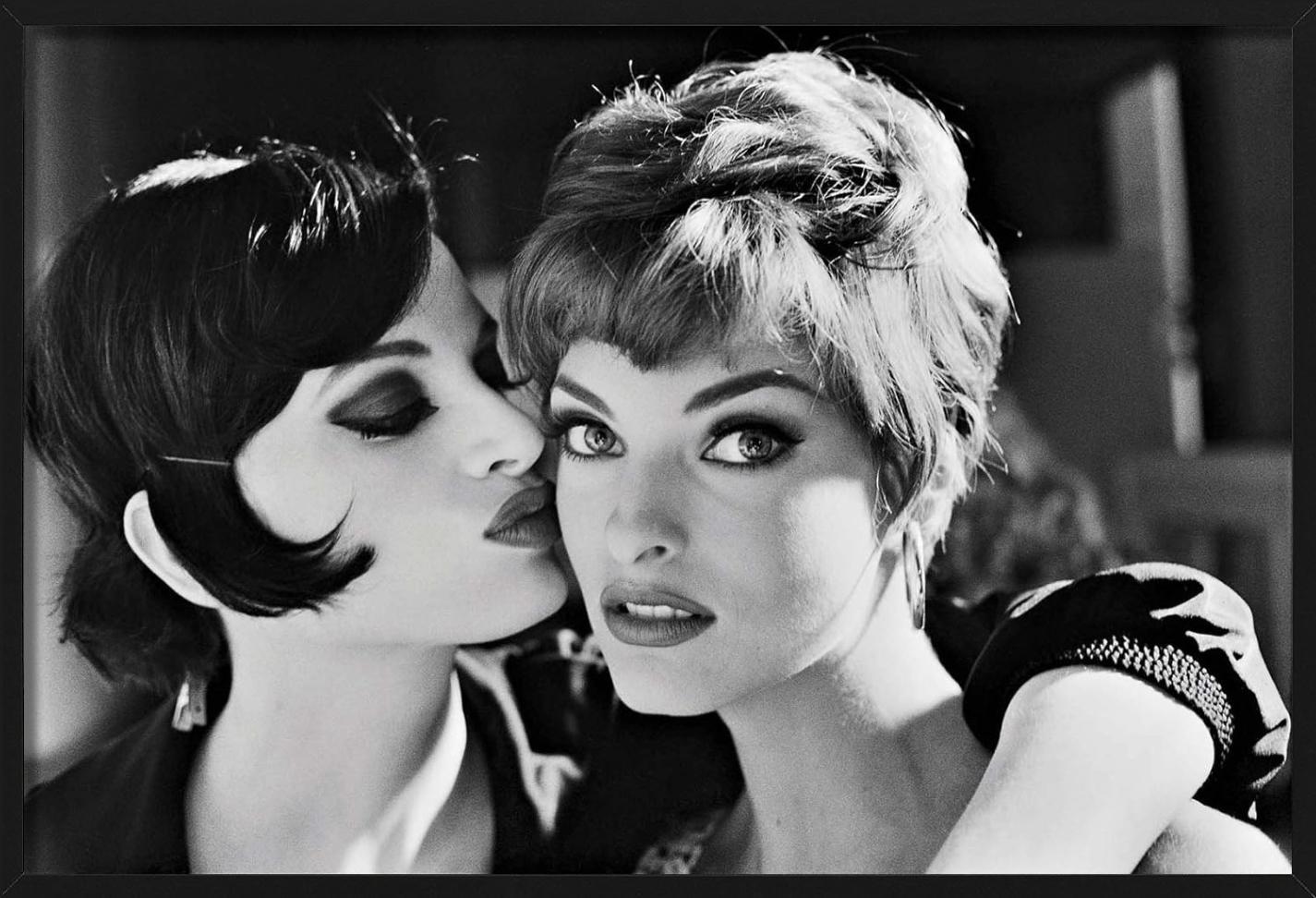 Beautiful black and white portrait of supermodels Kristen McMenamy and Linda Evangelista. Both wear heavy makeup and wigs, Kristen gives Linda a kiss on her cheek. This artwork was captured by Arthur Elgort in 1991.

All prints are limited edition.