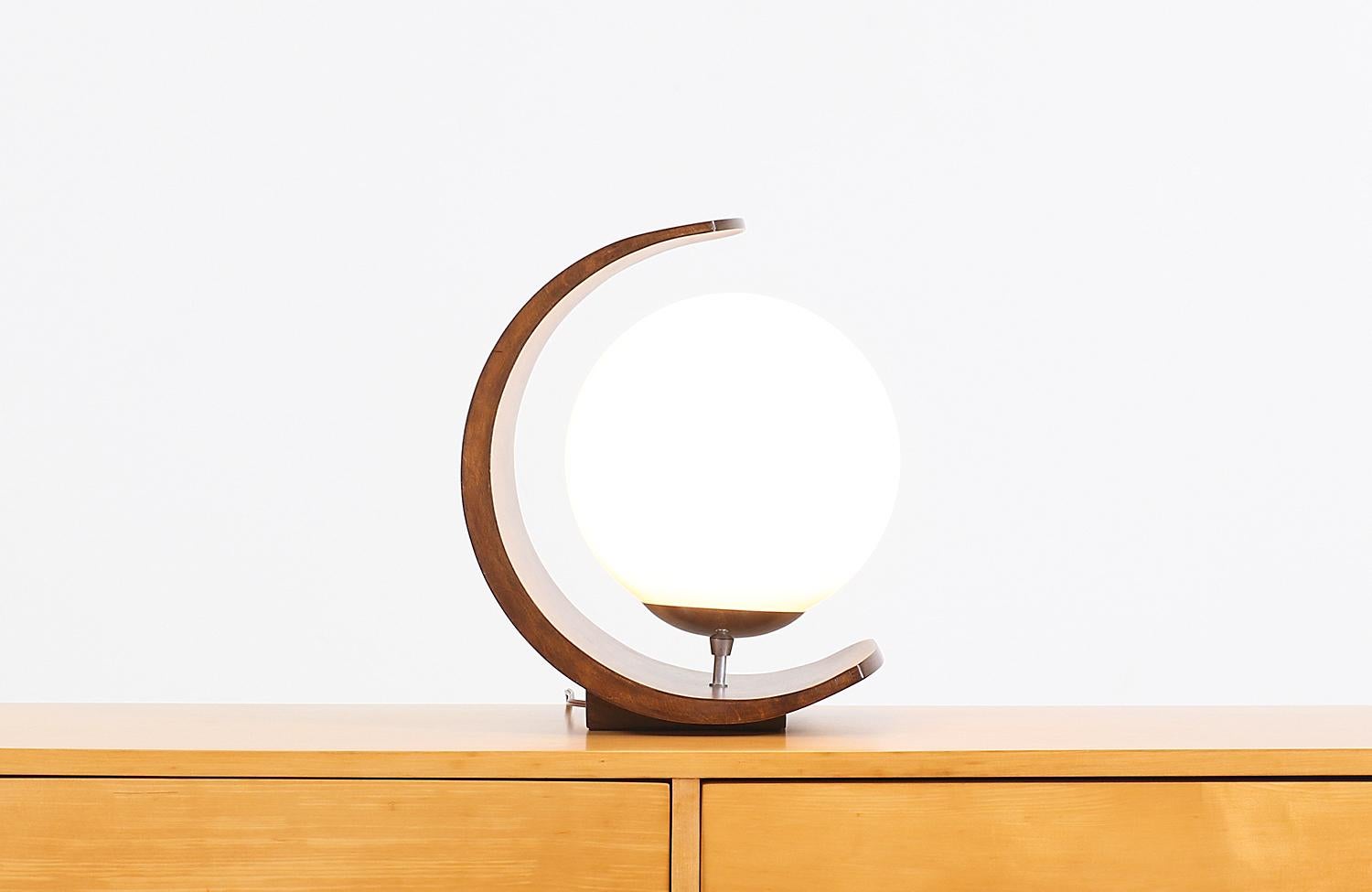 Dazzling modern table lamp designed by Arthur Jacobs for Modeline of California in the United States, circa 1960s. This beautiful table lamp features a quality crafted rounded walnut wood frame with a sculptural half-moon shape creating a luxurious