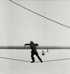 Malerbalken (S/W-Fotografie aus den 1950er Jahren von einem an einem Draht hängenden Mann)