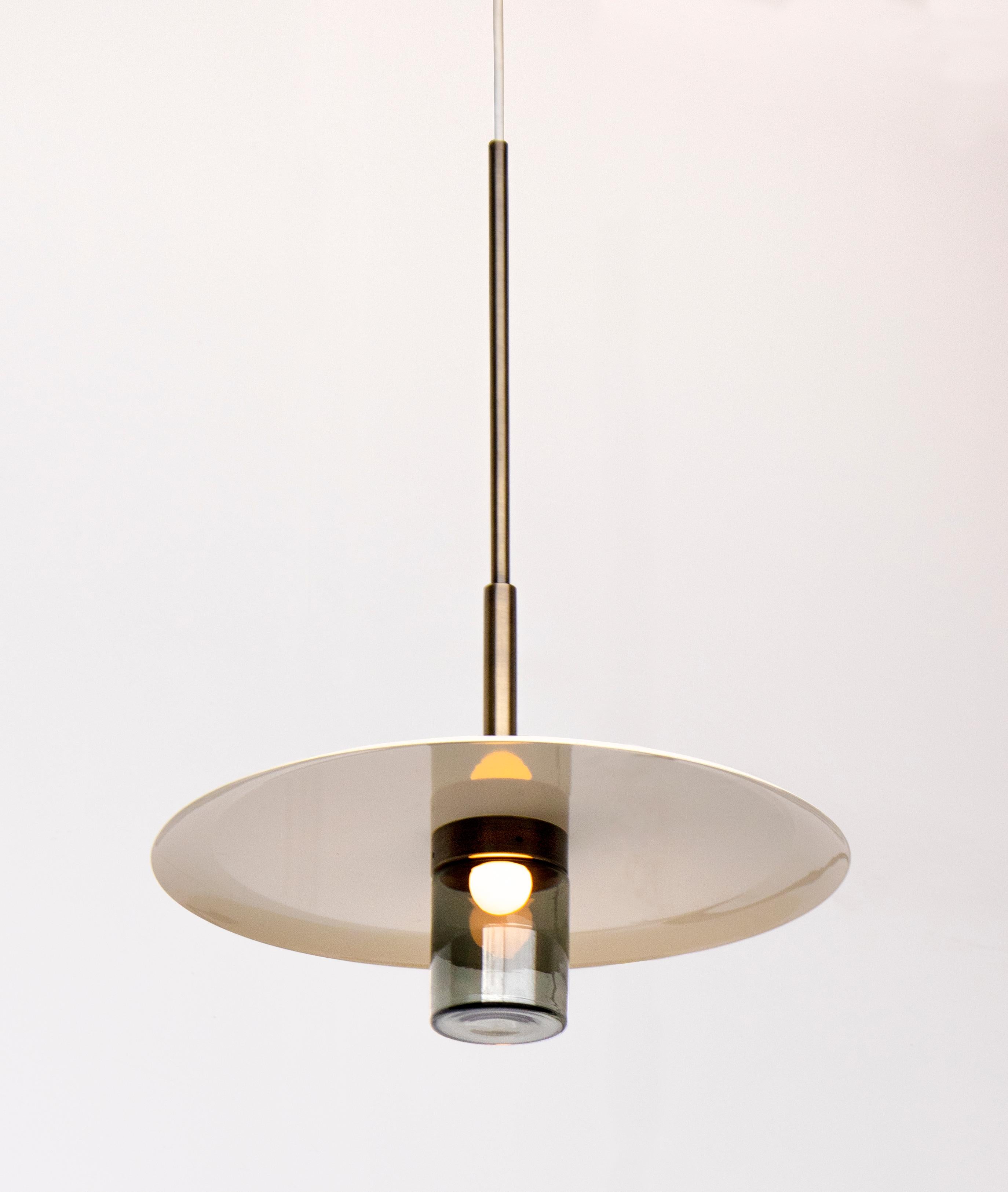 The Arthur pendant’s shade can be powder-coated in a variety of colors. A hand blown glass cylinder shines light on this surrounding surface. This versatile pendant can function as a solo attraction hanging above a small cocktail table or in a