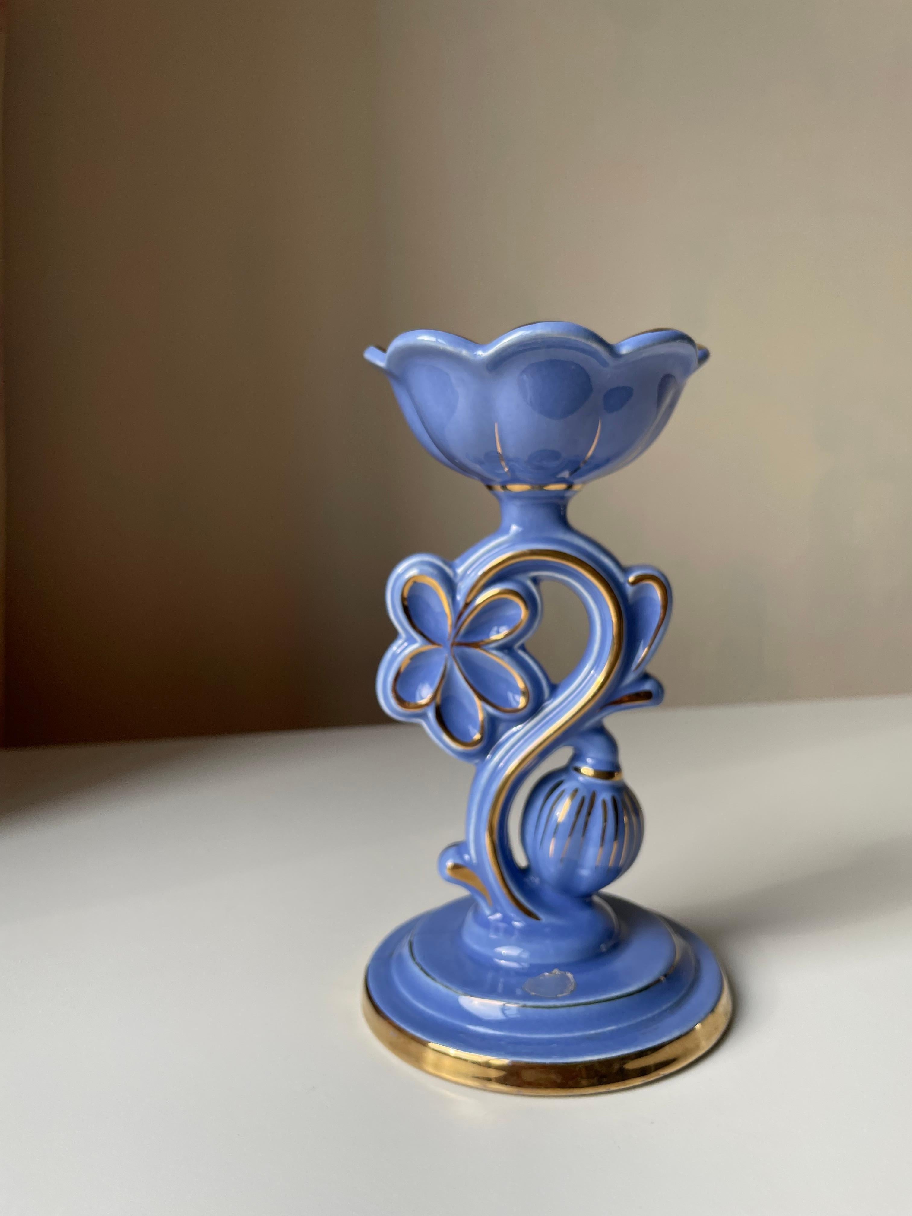 Romantic art nouveau style blue porcelain candlestick with a slight lilac tint, golden accents and decorative lines. Sculptural floral decor with top part resembling an open flower in which the candle is placed. Original silver colored label
