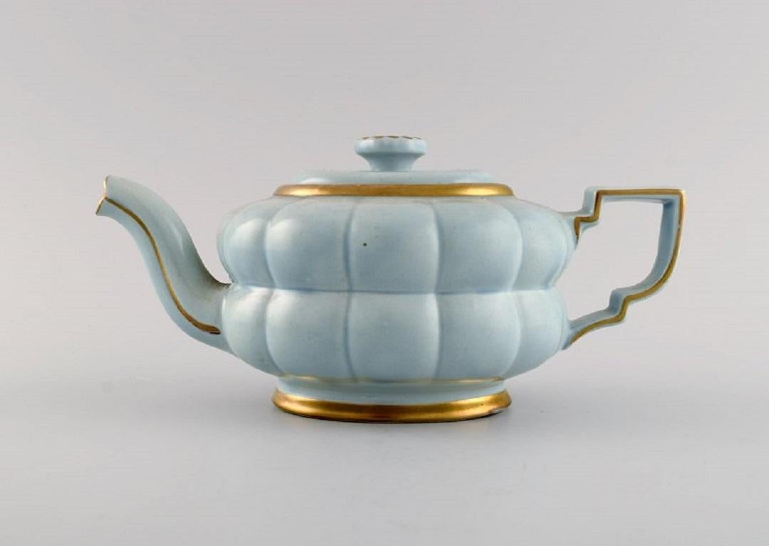 Arthur Percy for Upsala-Ekeby / Gefle. 
Complete Art Deco Grand tea service in pastel blue porcelain with hand-painted gold edge for five people. 
1930s / 40s.
Consisting of five teacups with saucers, five plates, sugar bowl and teapot.
The cup