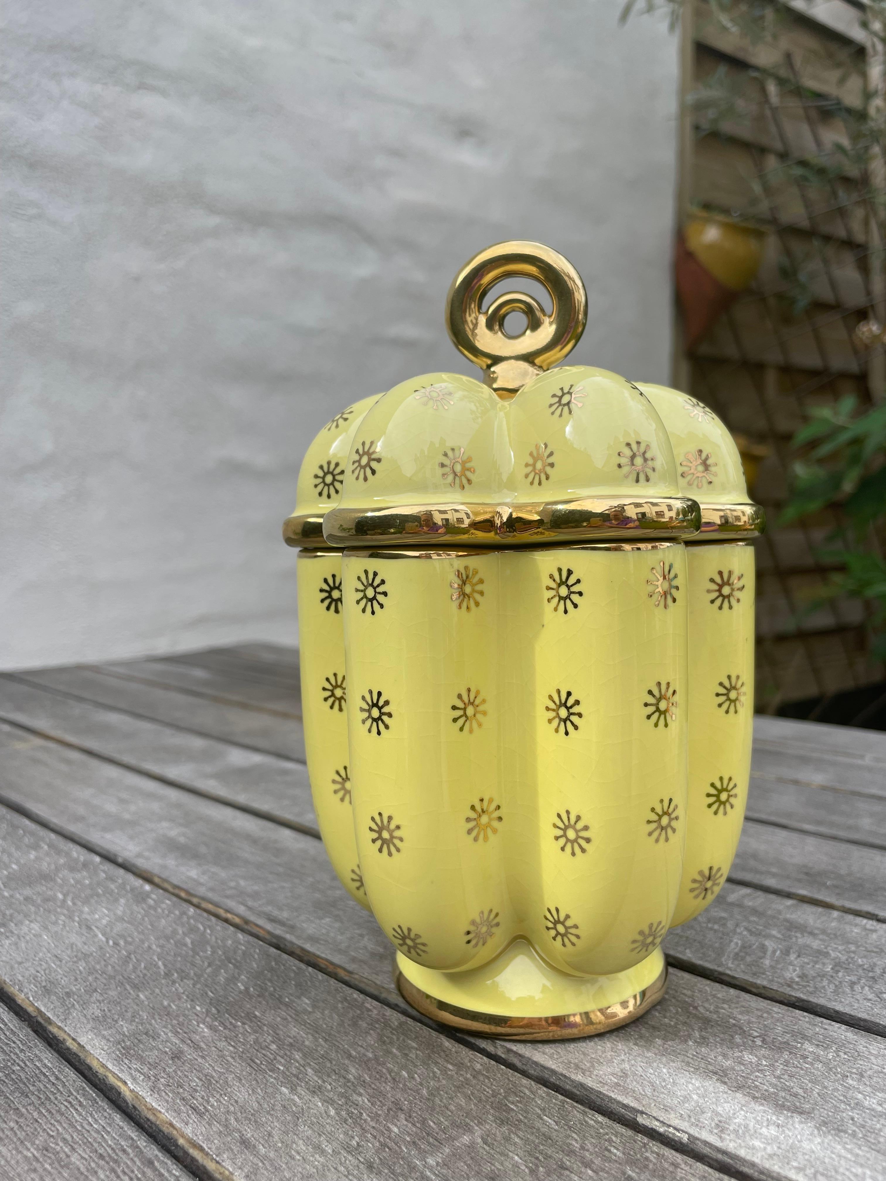 Swedish midcentury modern bright yellow porcelain lidded jar with vertical wavy shape. Stylized golden starshaped flower decor, golden lines and round golden top. Stamped under base. Beautiful vintage condition.
Sweden, 1950s. 