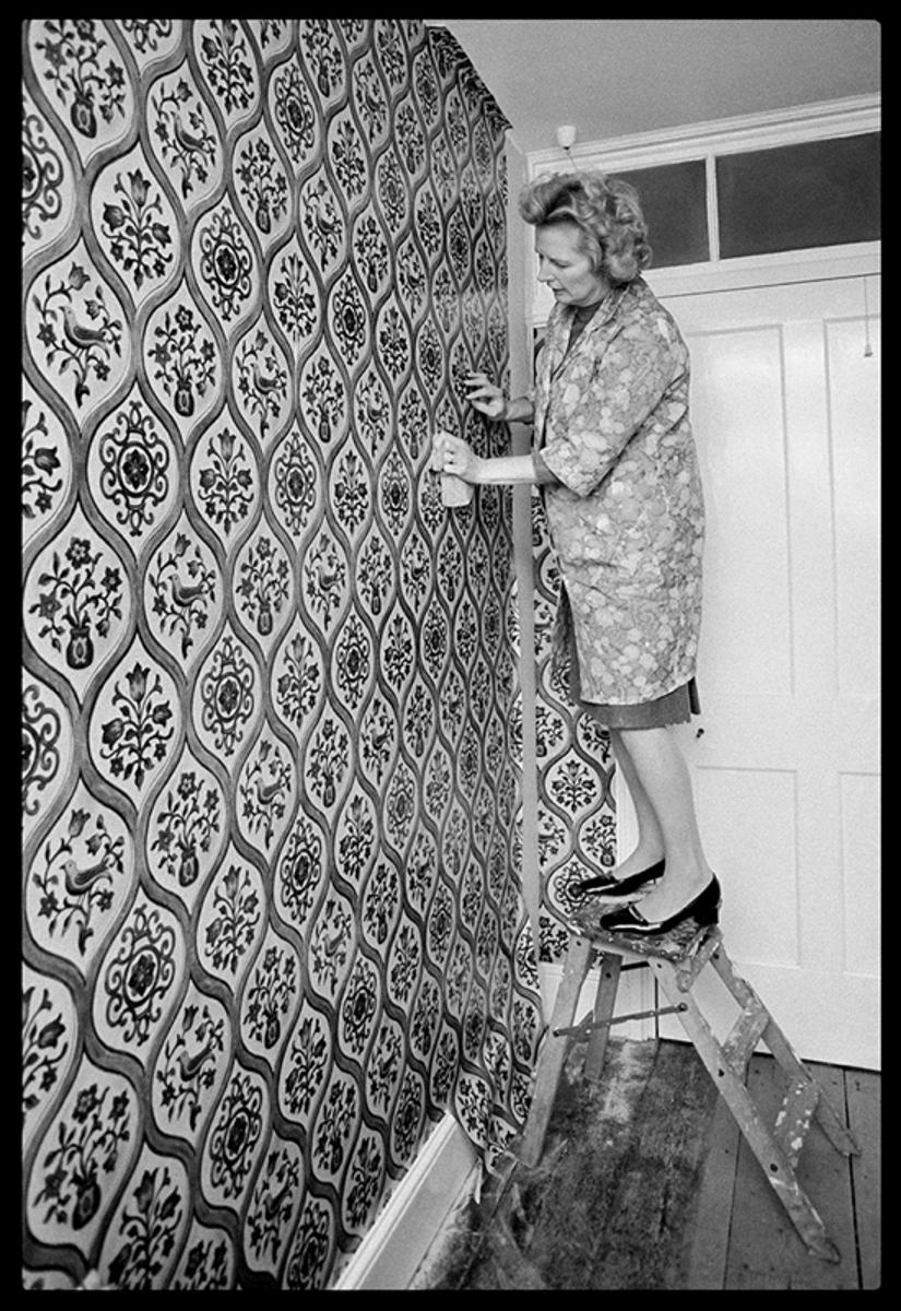 Hung Parliament 

by Arthur Steel

Hung Parliament – Margaret Thatcher hanging wallpaper,Kent, 1975 

Margaret Thatcher (Known as The Iron Lady) hangs wallpaper at her country retreat for publicity purposes. Margaret is photographed wearing a floral