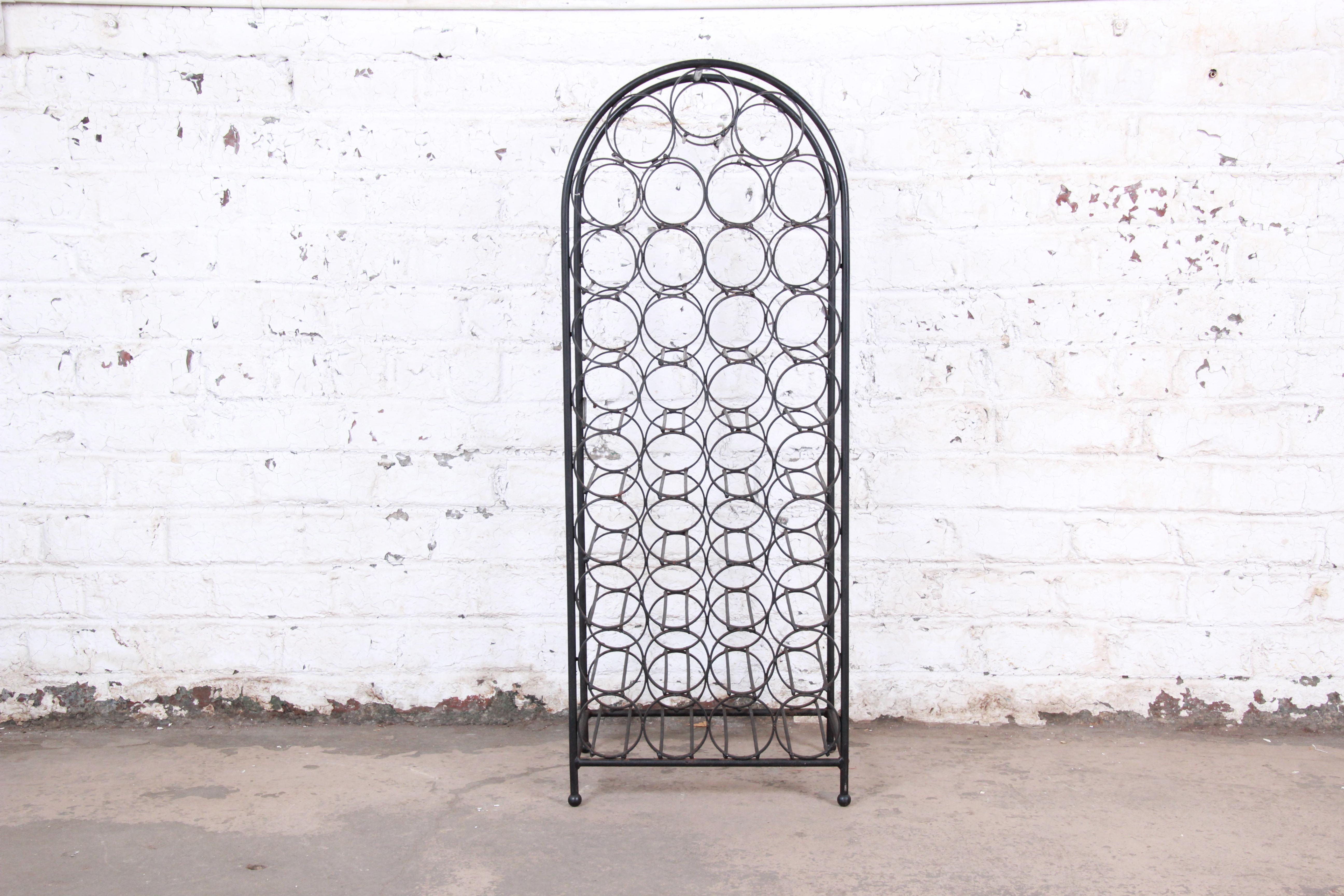 A unique Mid-Century Modern freestanding 39-bottle wine rack designed by Arthur Umanoff. The rack has a heavy wrought iron frame with a stylish arched top. It is sturdy and in very good original vintage condition, with normal wear and patina from