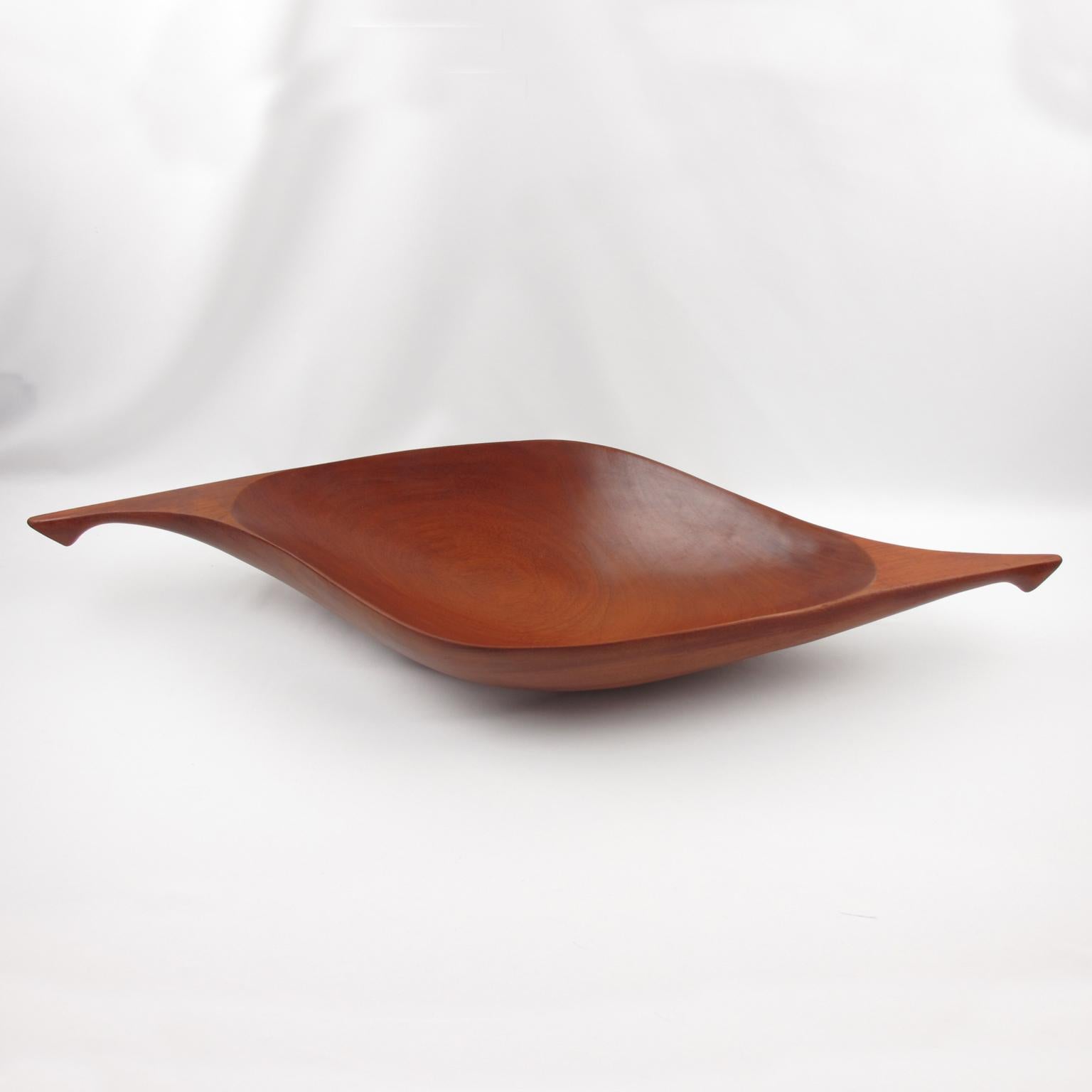 This modernist wooden canoe bowl or centerpiece from the Taverneau Collection was designed by Arthur Umanoff for Raymor and produced in Haiti. 
The sleek and premium oversized shape has a typical Danish flair. The carved and oiled tropical wood is