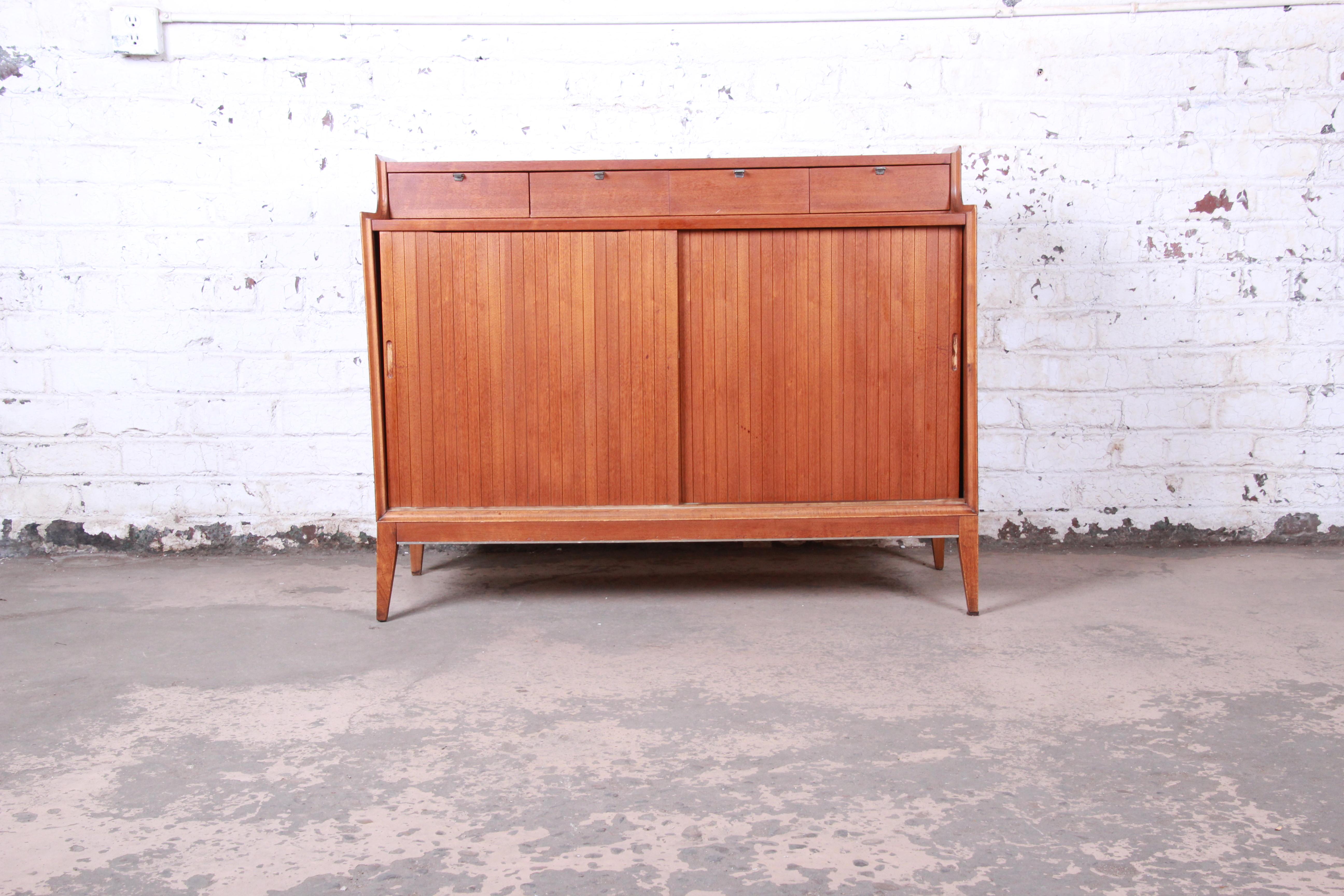 A gorgeous Mid-Century Modern sideboard credenza or bar cabinet designed by Arthur Umanoff for Cavalier Furniture. The credenza features stunning walnut wood grain and sleek Mid-Century Modern design. It offers ample storage, with four small drawers